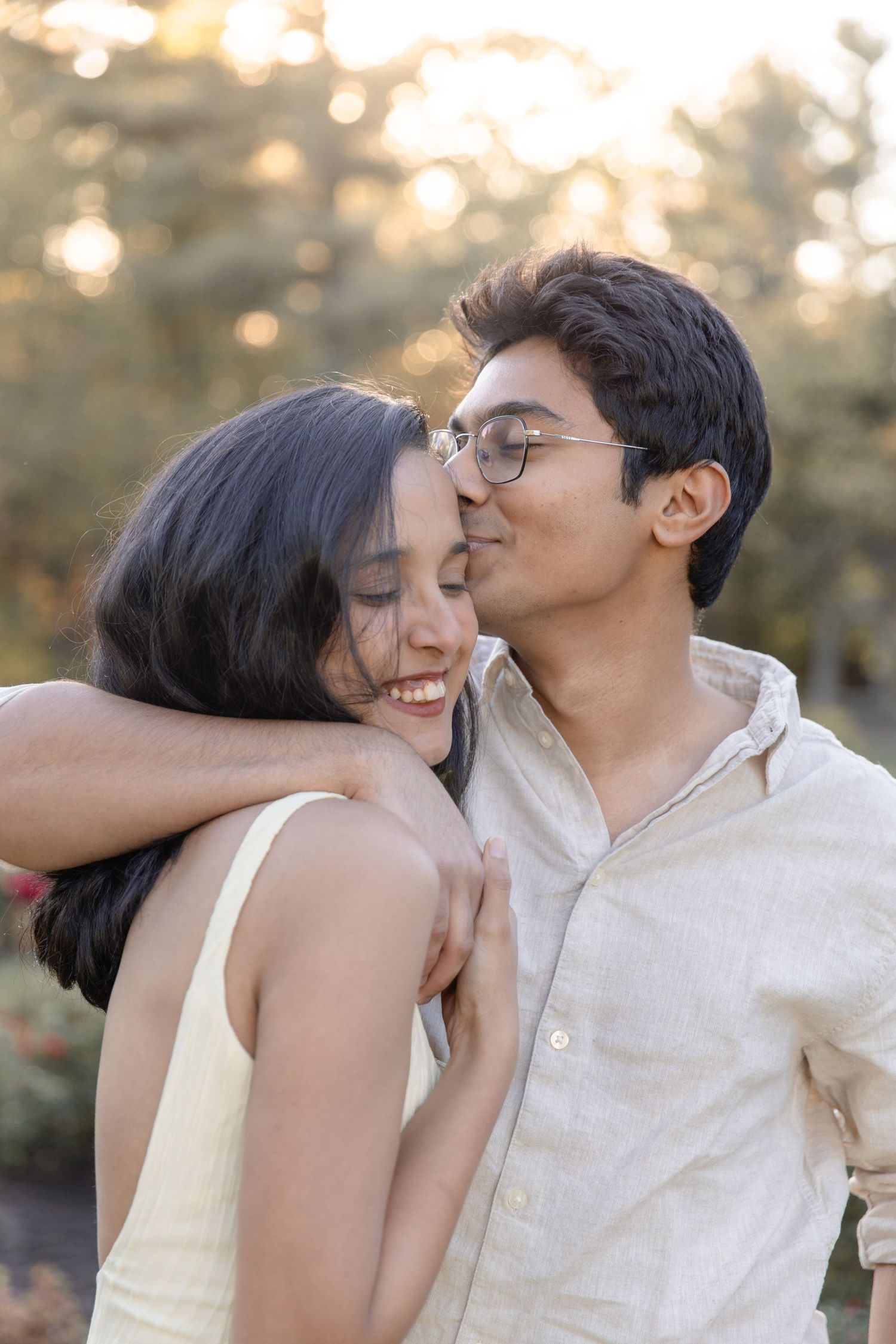 A tender romantic moment between a couple sharing laughter and affection in soft golden sunlight.