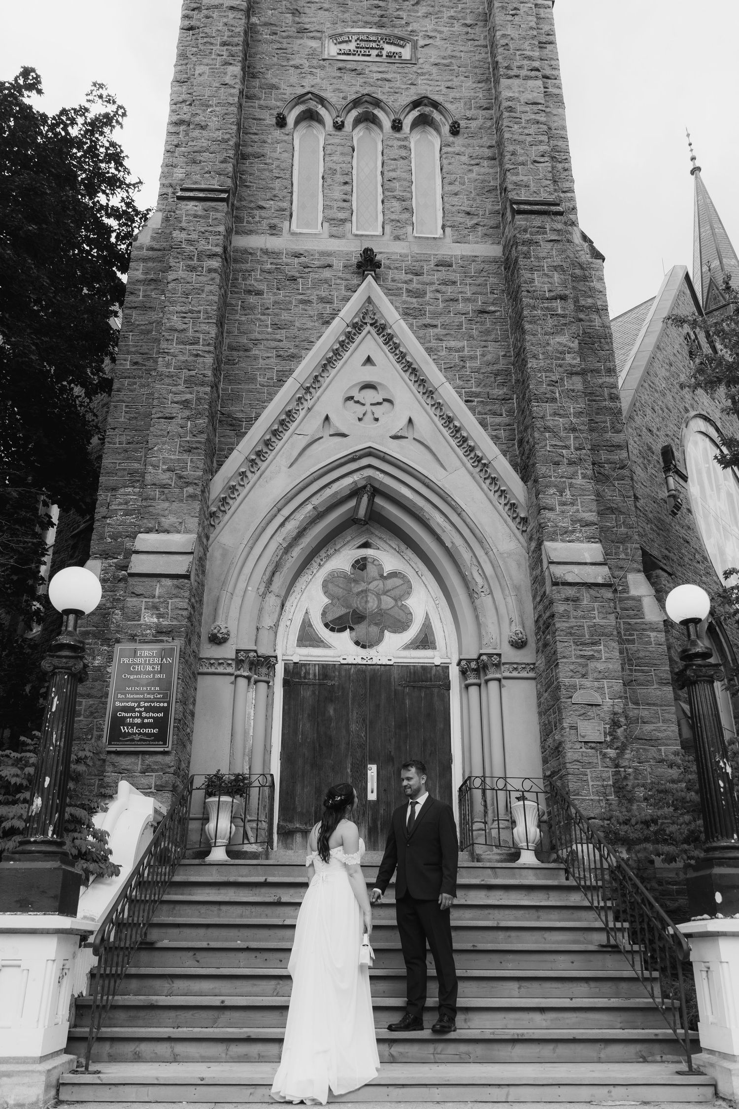 Black and white photo series of a couple standing on stone church steps with Gothic arched doorway and architecture.