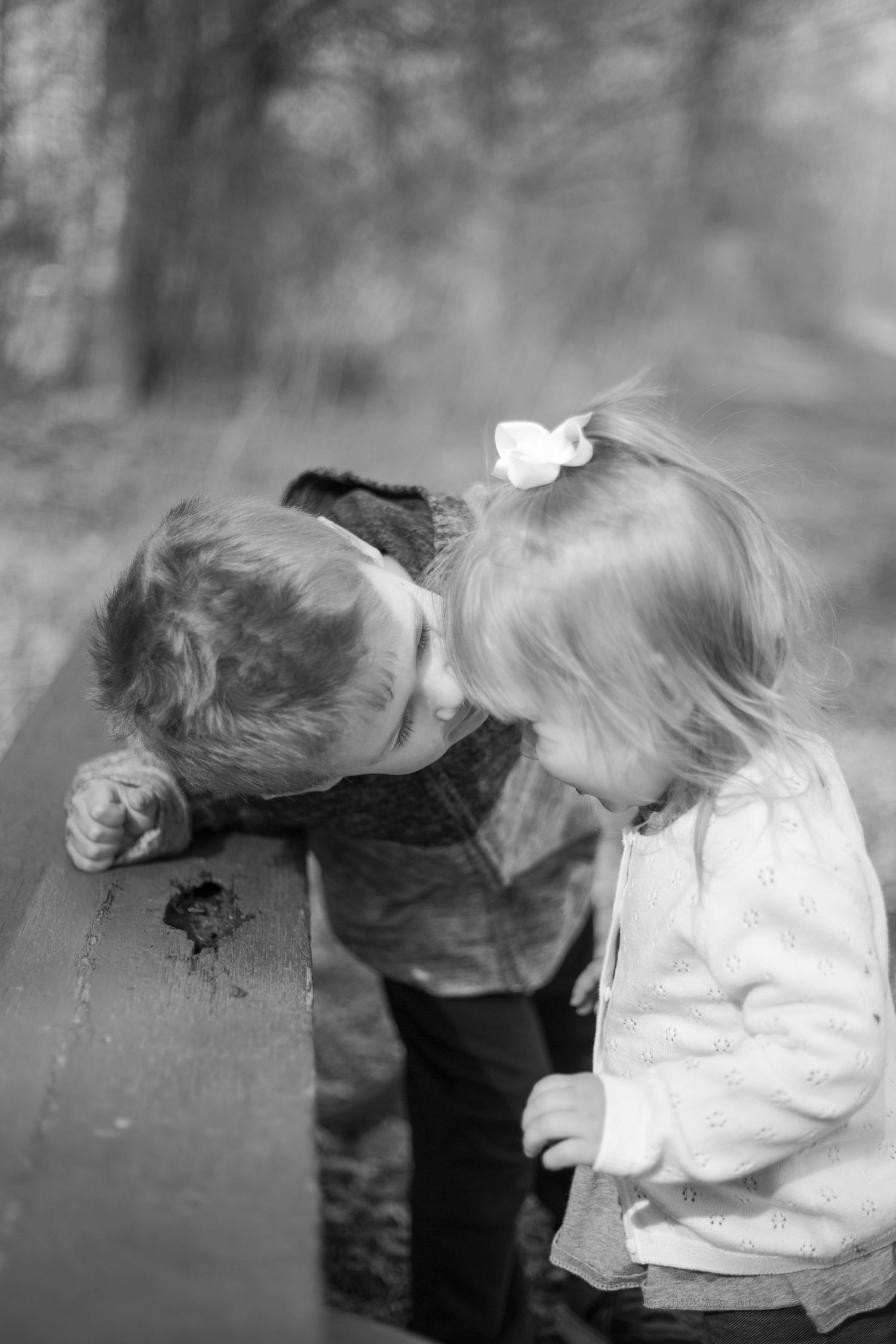 Two young children share a sweet, candid moment together in a black and white photograph.