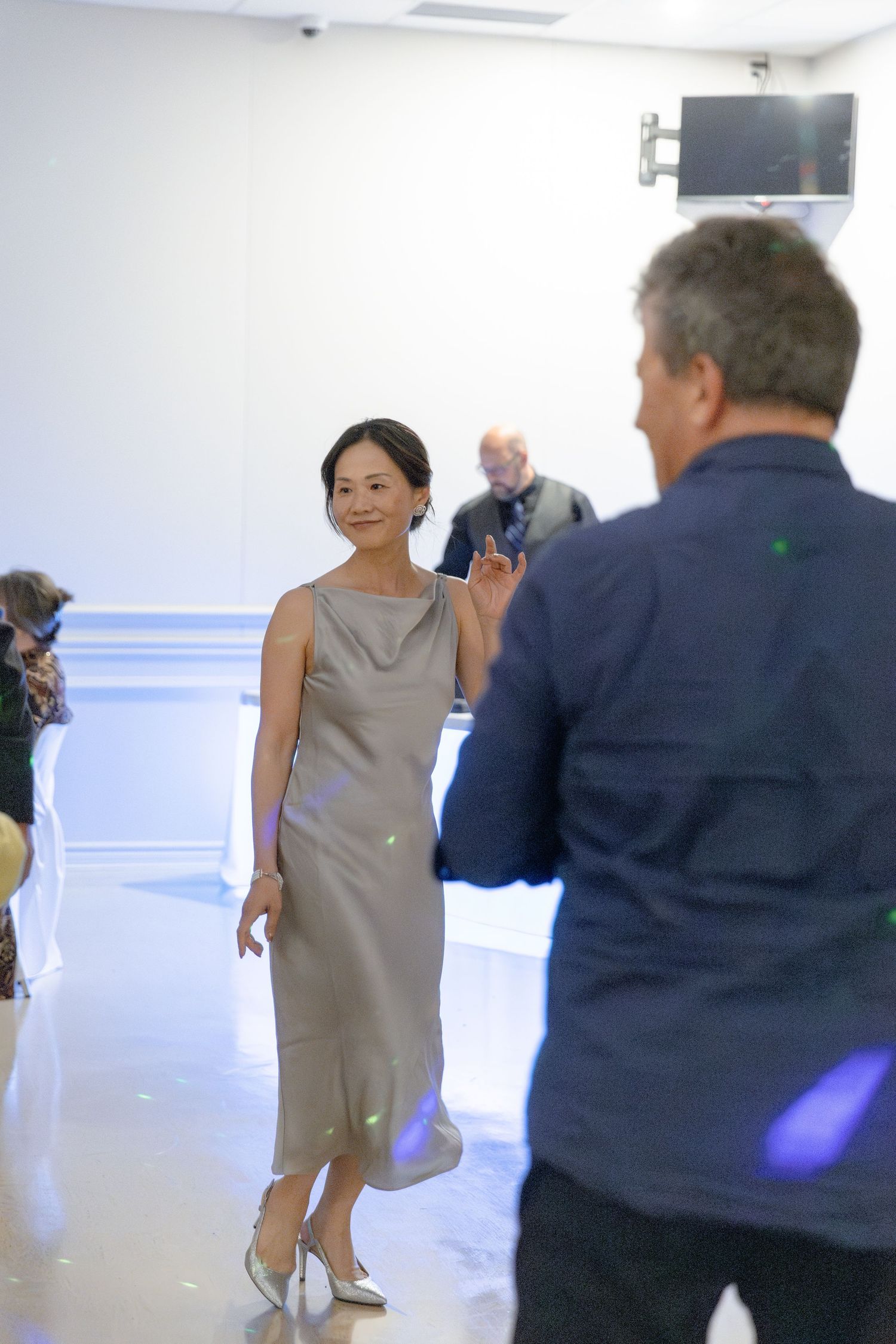 People dancing together in a bright white room with fluorescent lighting and blue accents.