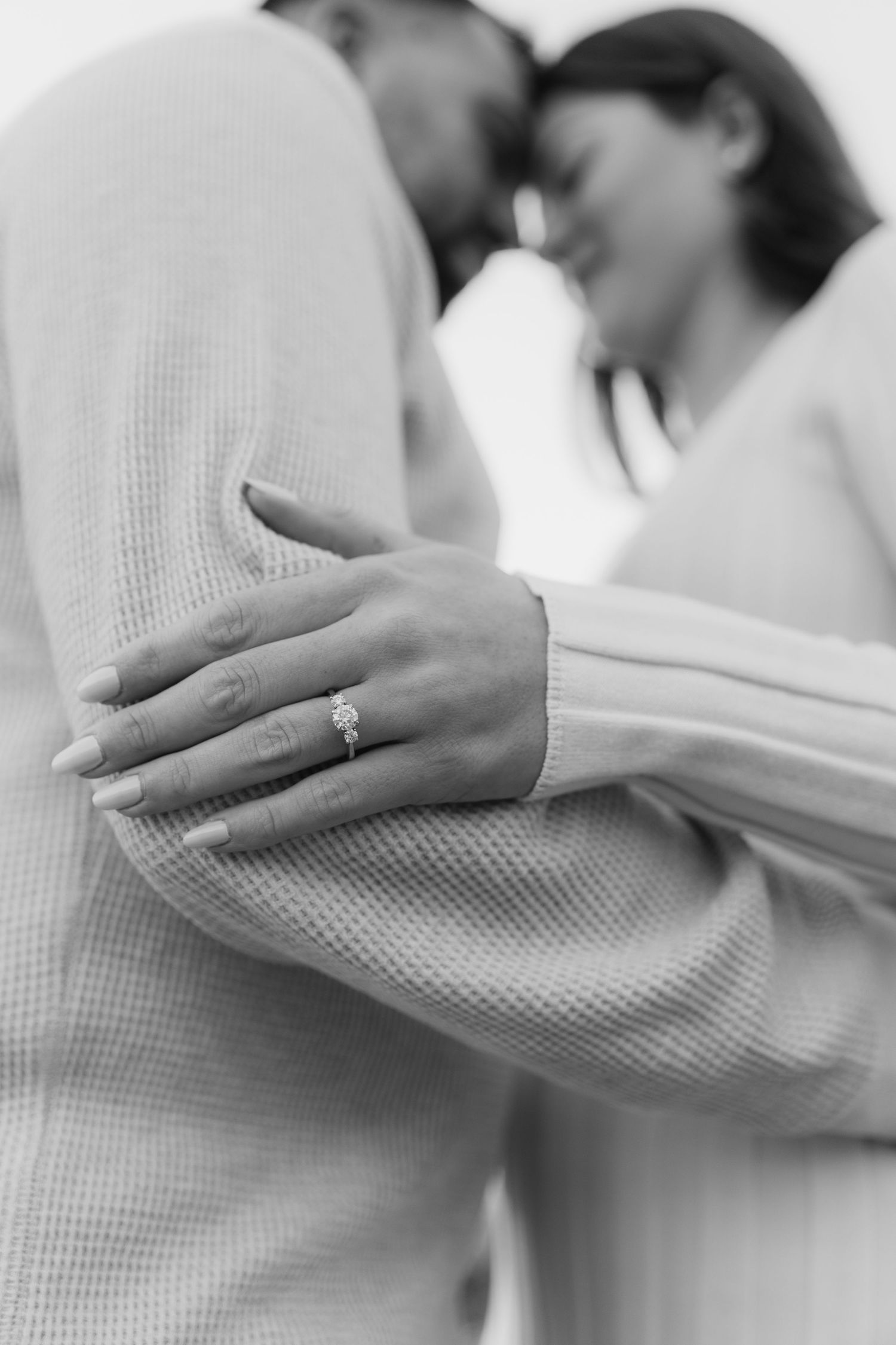 Close-up sequence of hands wearing a white robe holding a diamond engagement ring in soft focus.
