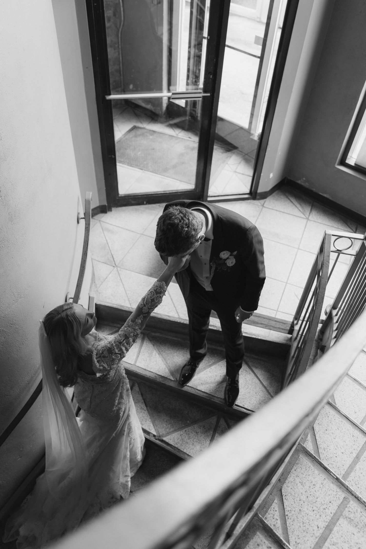 Black and white security camera footage shows someone ascending a stairwell in a building interior.