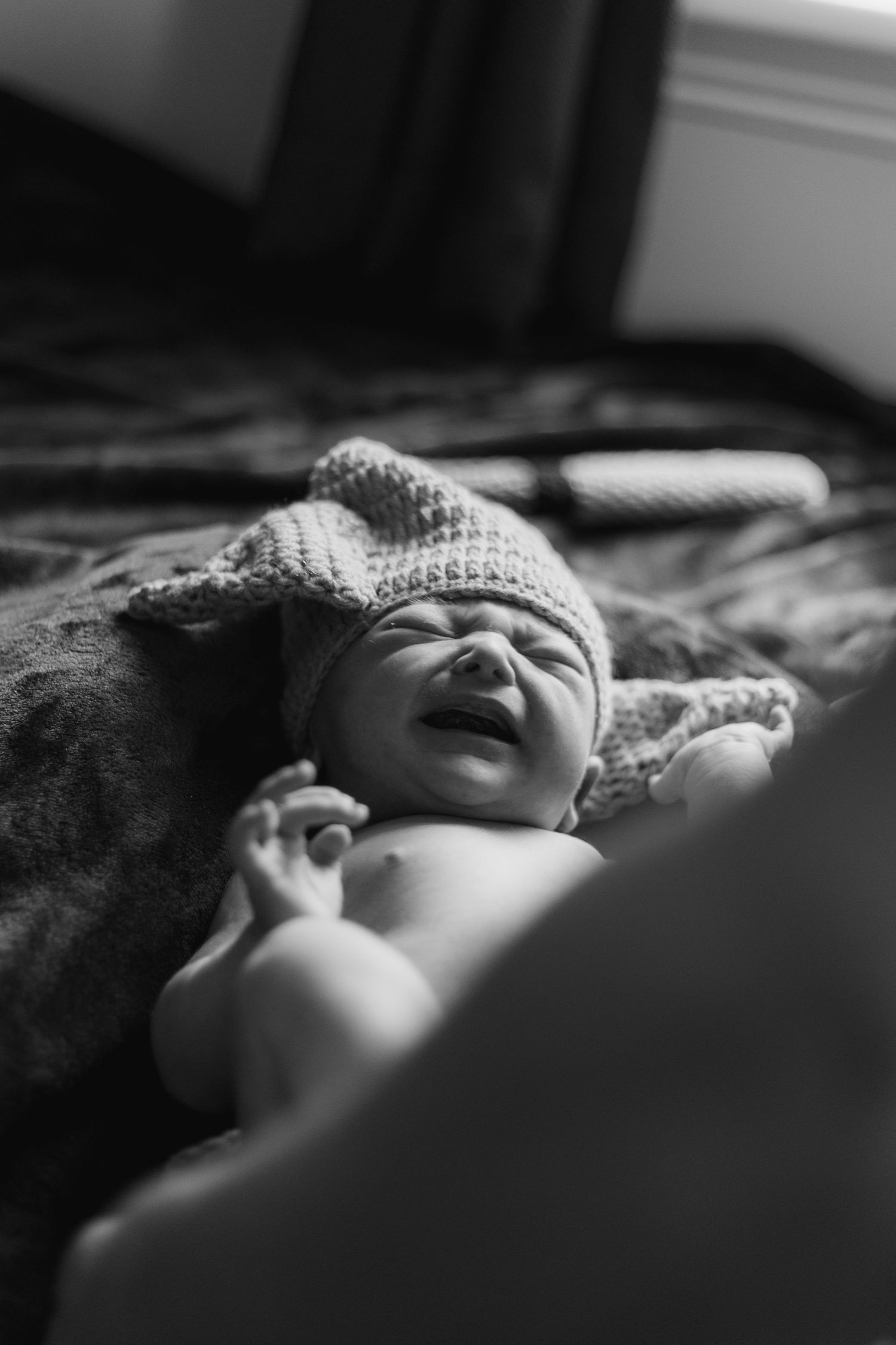A black and white artistic portrait of a sleeping baby swaddled in blankets.