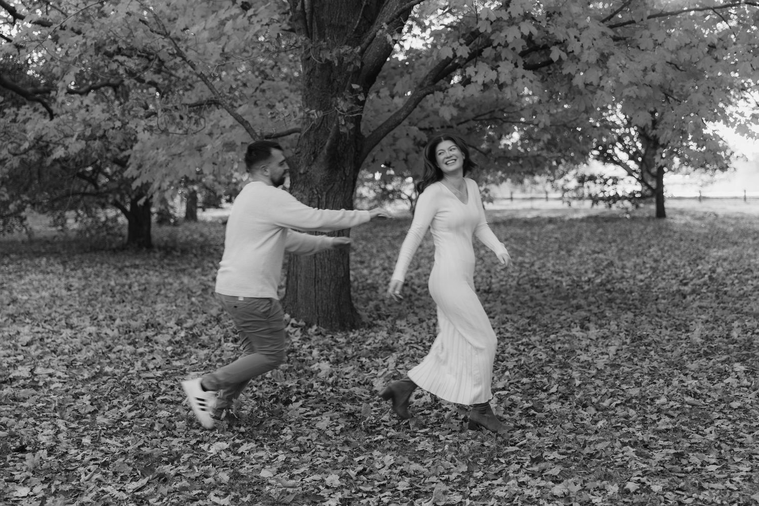 A sequence of black and white photos shows playful moments in a park with autumn leaves scattered on the ground.