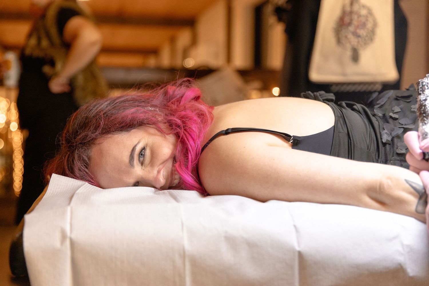 A person with pink hair lies sleeping on a white pillow and bedding.
