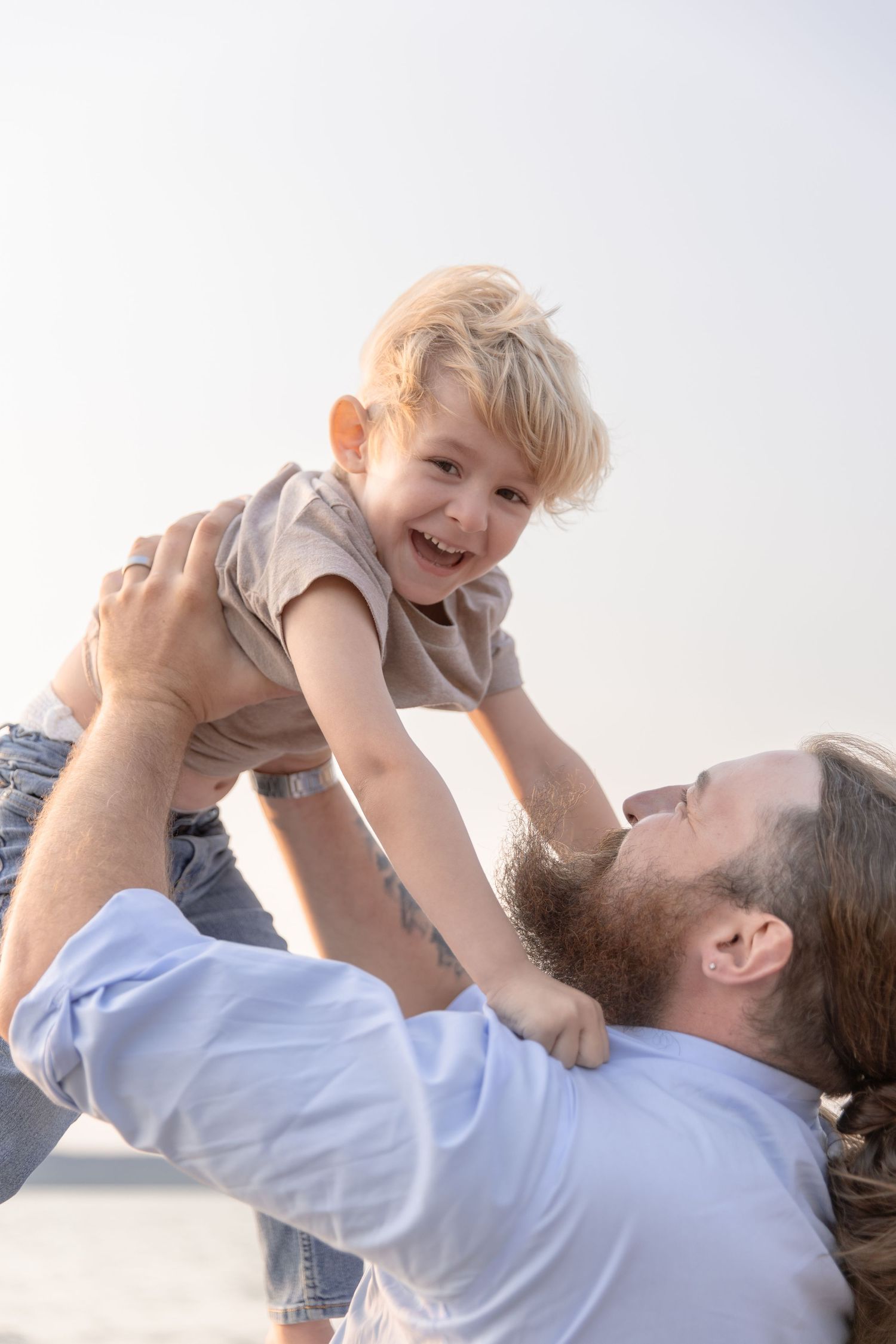 A series of joyful candid moments showing a parent playfully lifting a small child in the air against a bright sky.