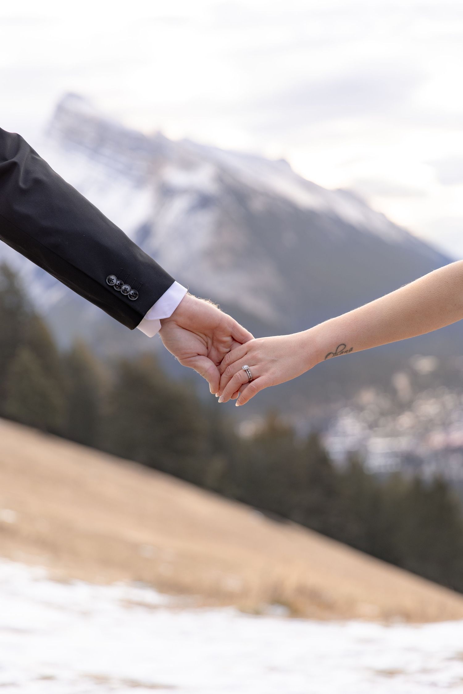 Two hands reaching towards each other against a snowy mountain backdrop, symbolizing connection and unity.