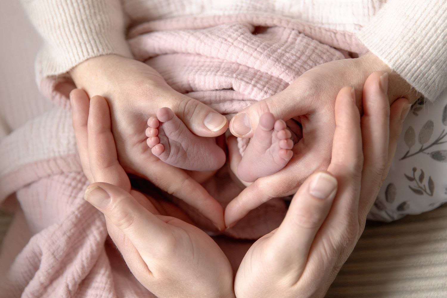 Close-up series of hands holding and caressing a newborn baby's tiny feet in soft lighting.