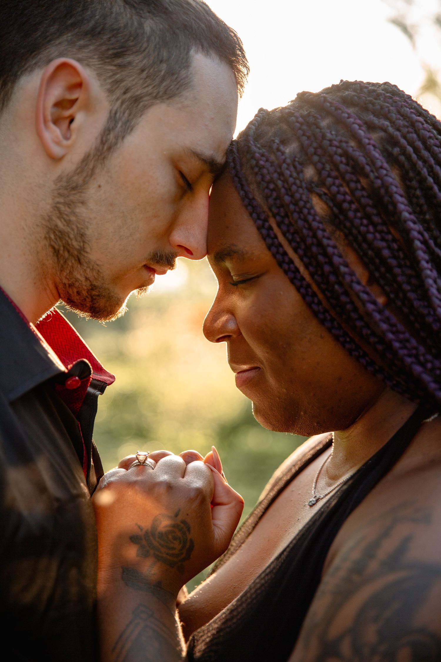 An intimate close-up portrait of an interracial couple sharing a tender moment against a warm sunset backdrop.