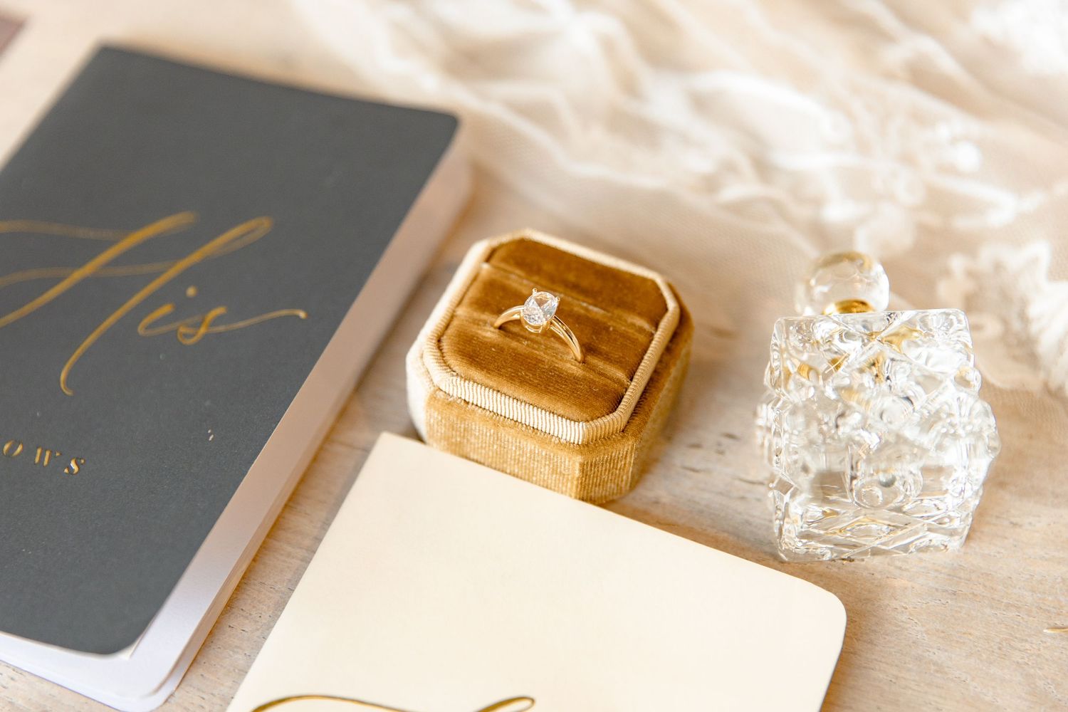 Elegant wedding stationery and accessories in gray and gold tones laid out on a light textured surface.