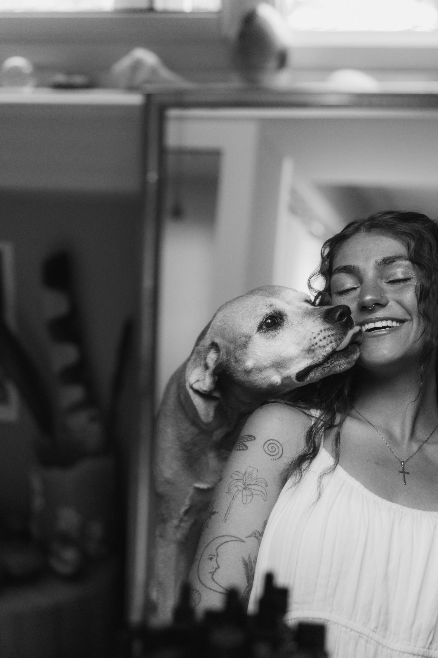A black and white photo series showing a dog lovingly licking someone's face in multiple tender moments.