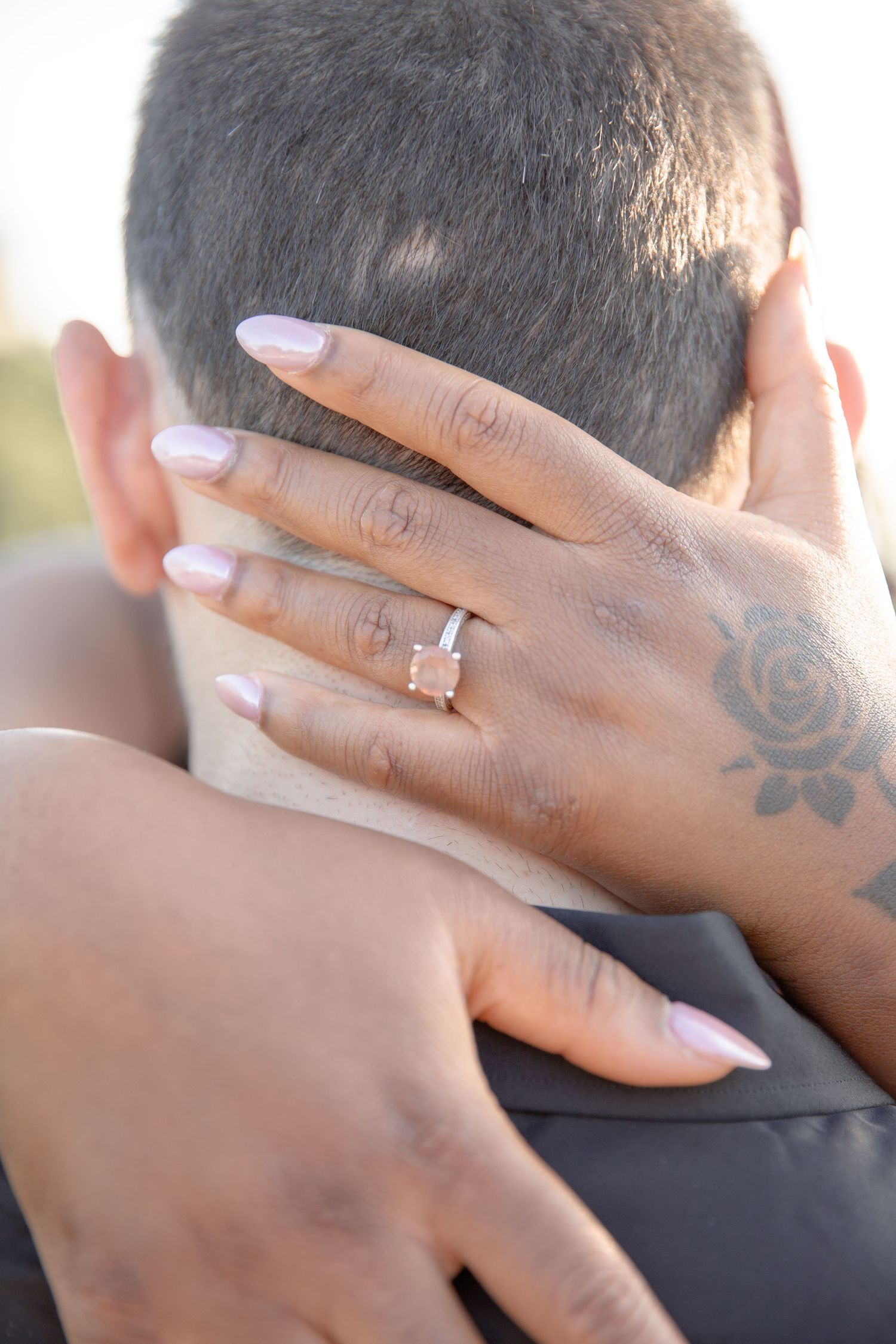 Close up of hands with a diamond engagement ring embracing during an intimate moment.