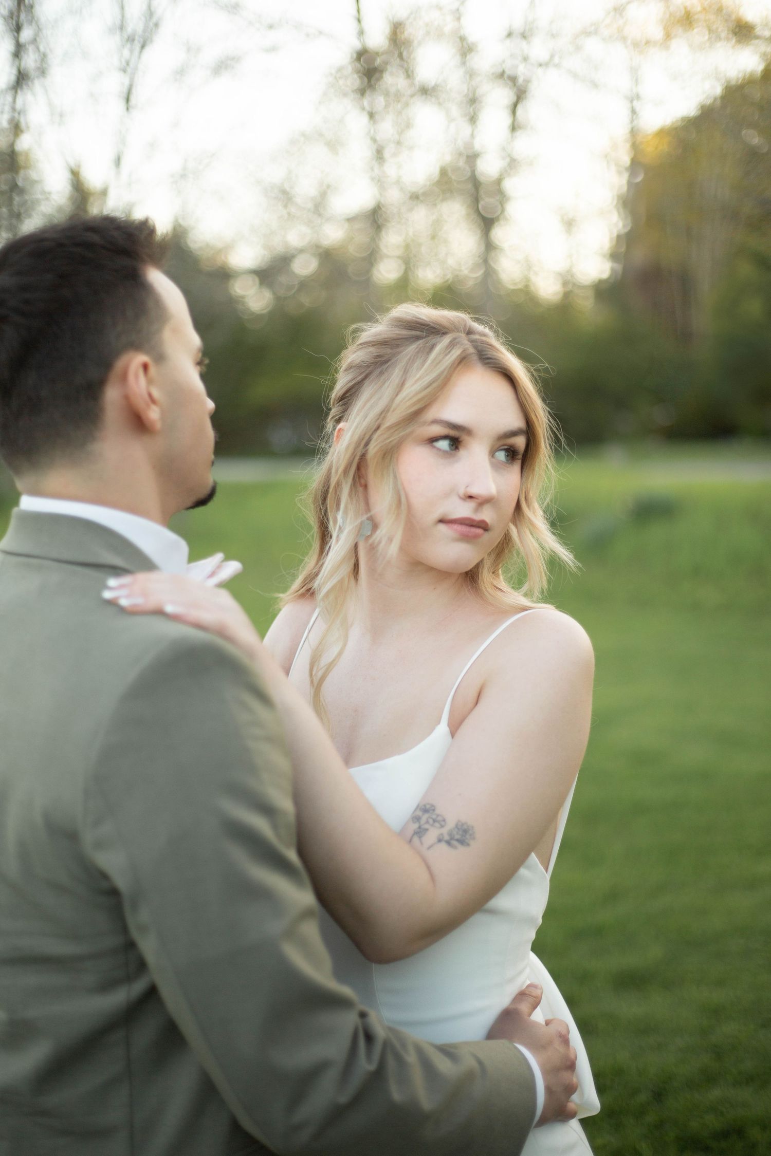 A romantic outdoor wedding portrait with a couple in gray suit and white dress sharing an intimate moment.