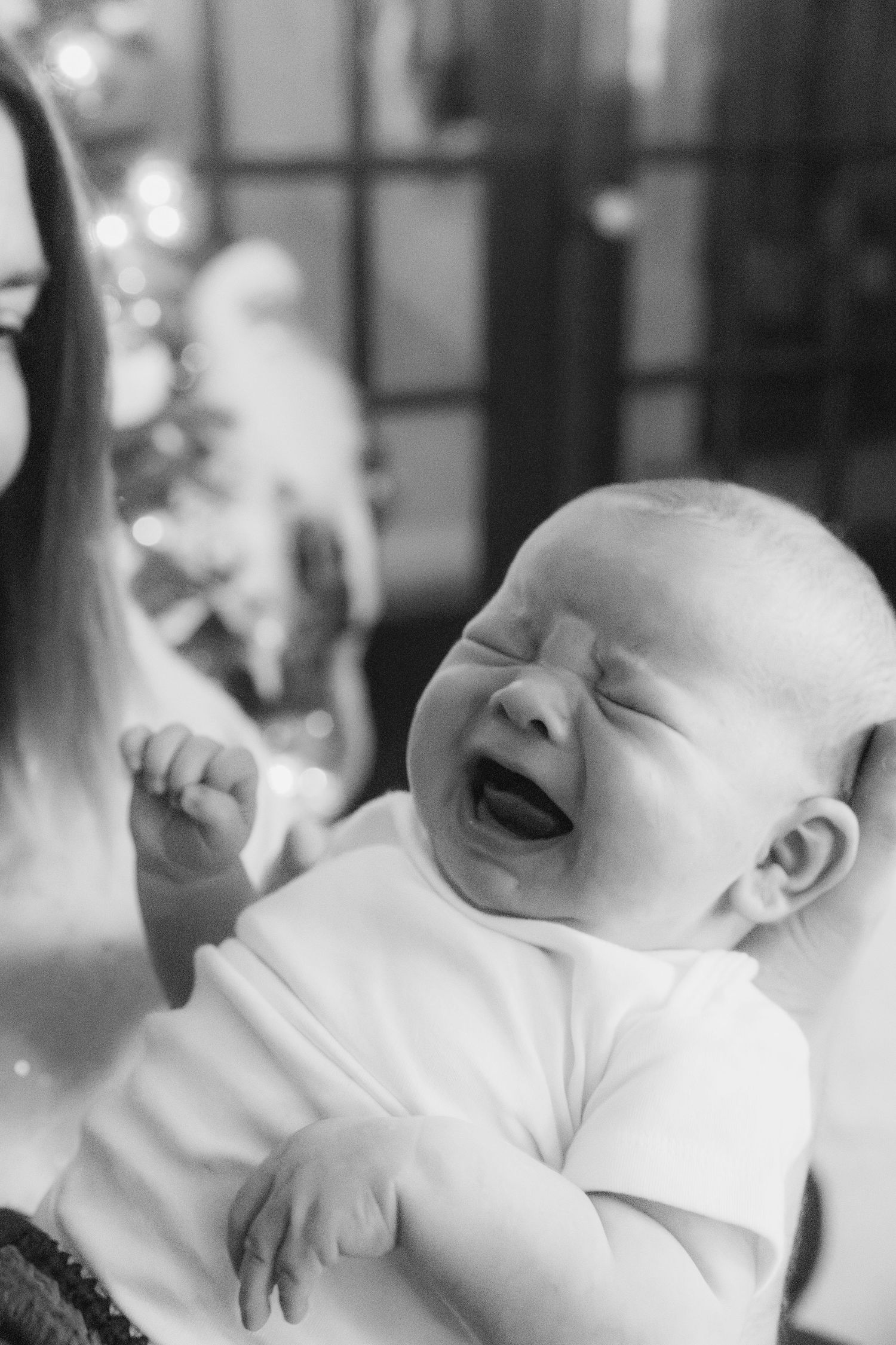 A series of black and white photos showing a sleeping baby in white clothing with various peaceful expressions.