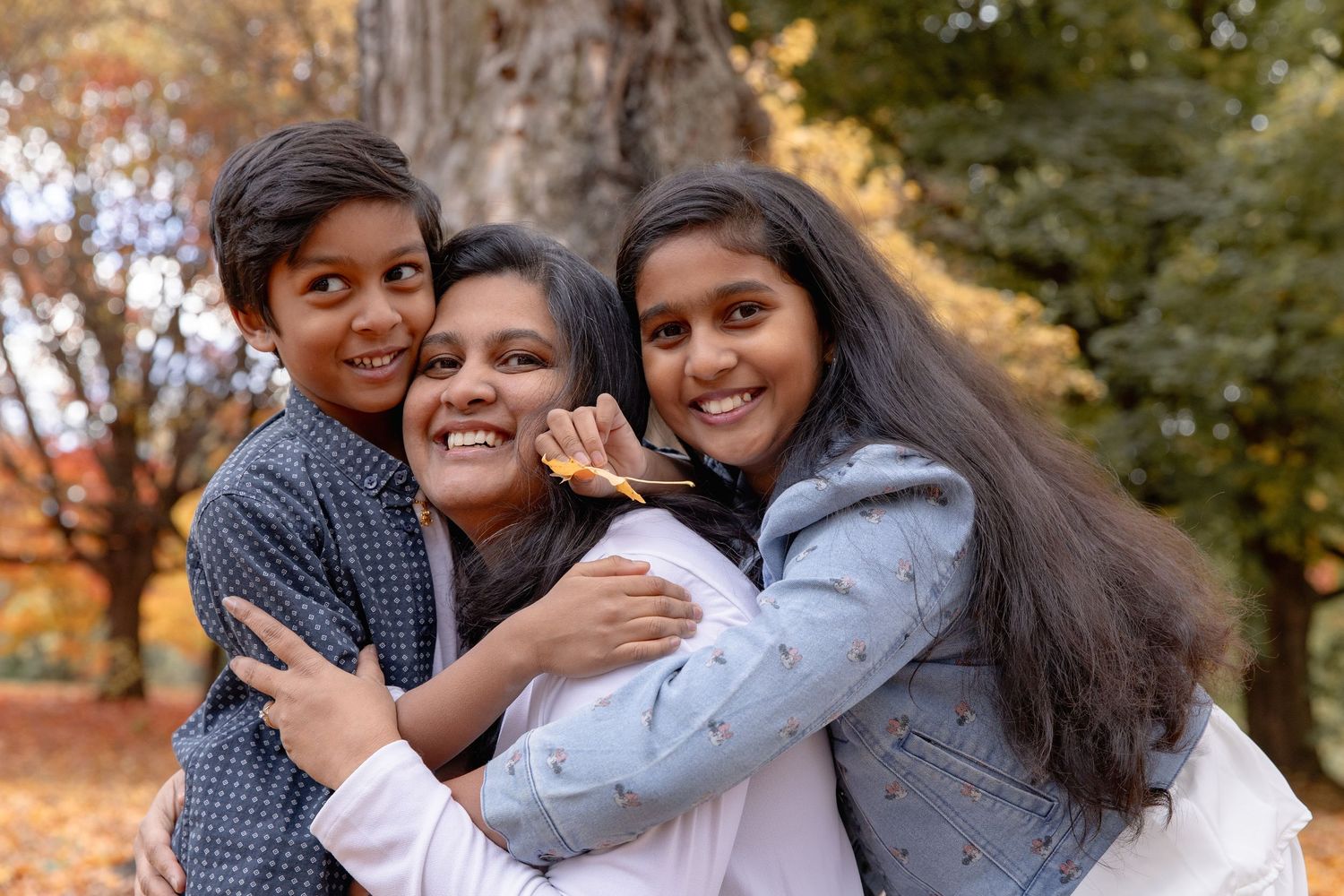 A group of friends laughing and embracing while taking outdoor photos during a golden sunset in a park.