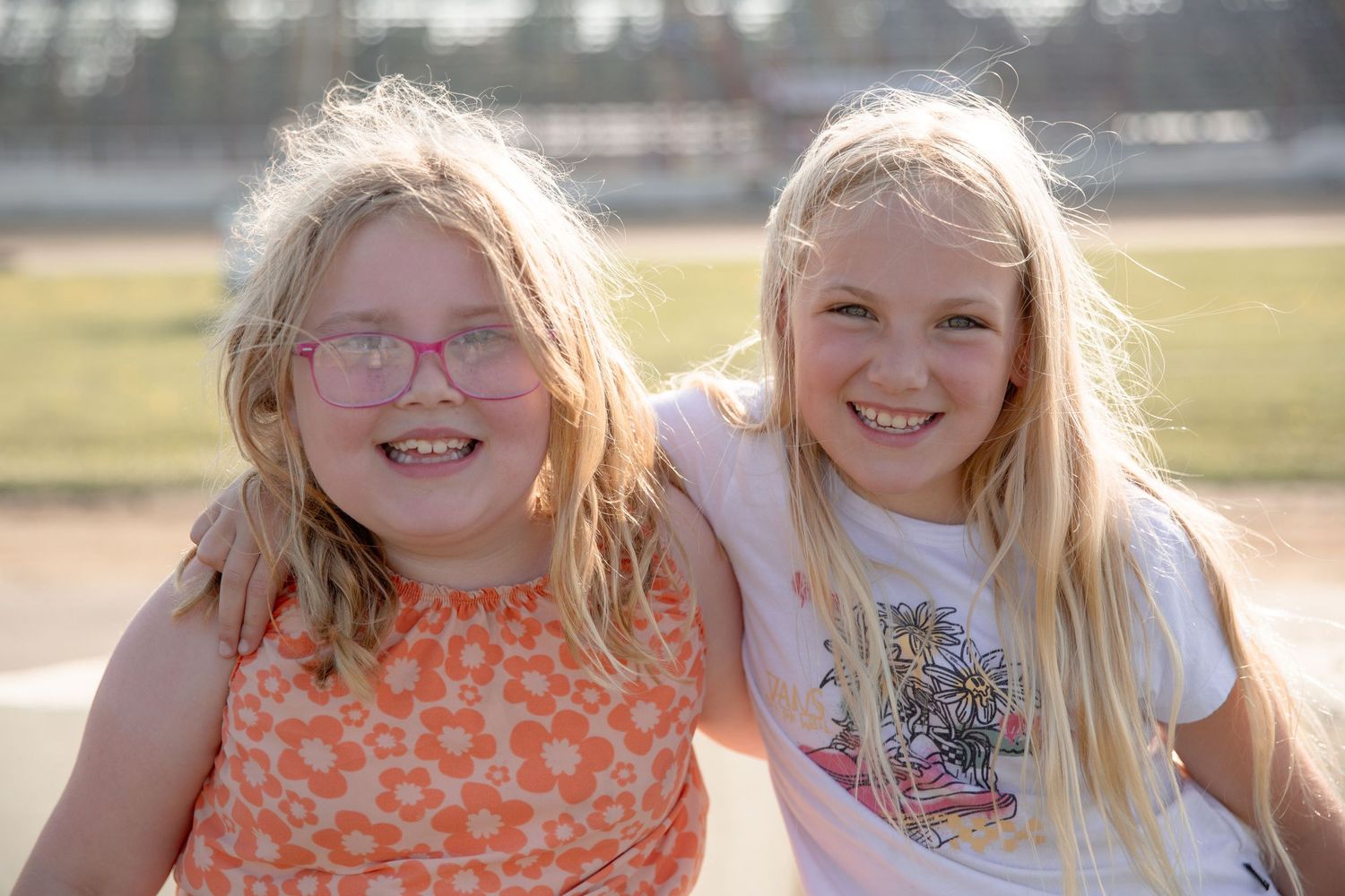 Two young children laugh and play together outdoors in natural lighting.