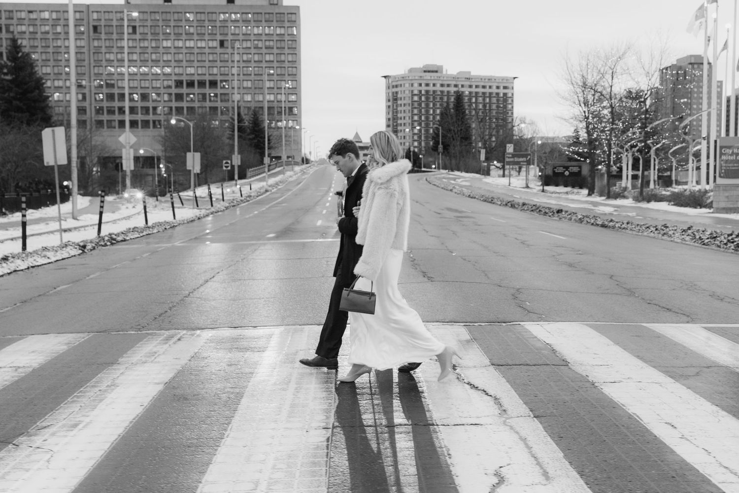 Black and white photo sequence showing a couple walking and dancing playfully on a snowy urban sidewalk.