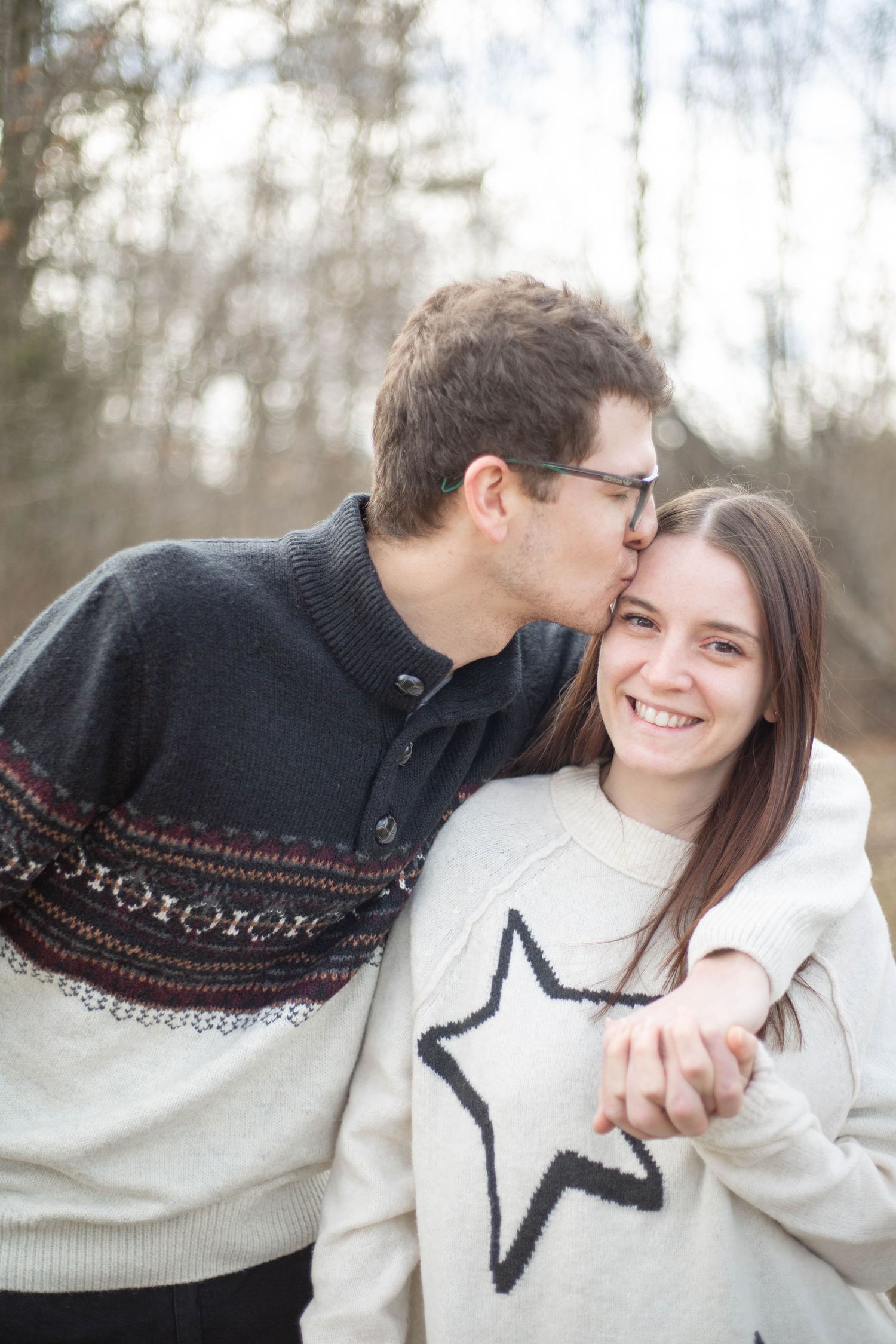 A happy couple in cozy winter sweaters share a tender moment outdoors on a cold day.