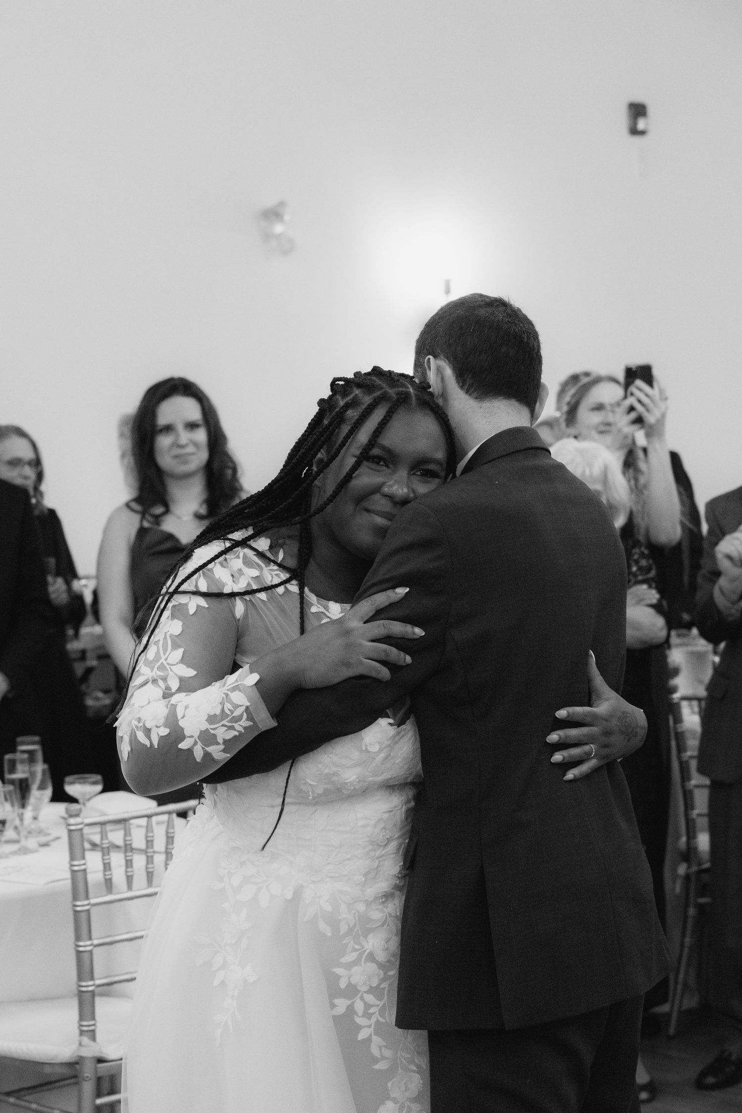 Black and white photo of a bride and groom sharing their first dance at a wedding reception.
