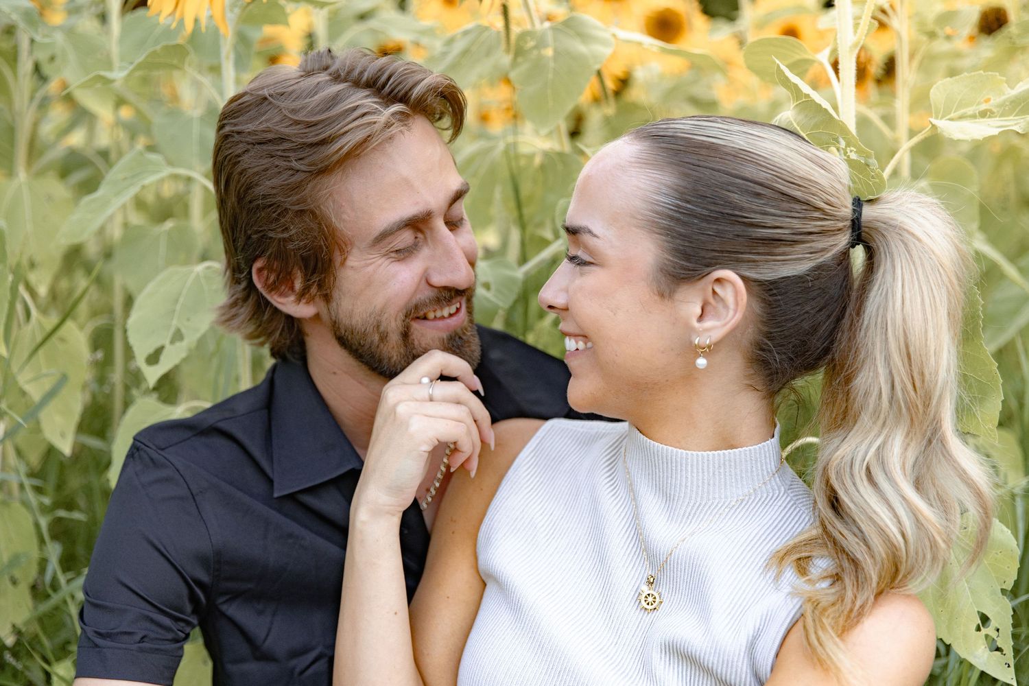 A couple shares joyful moments in a field of blooming sunflowers on a sunny day.