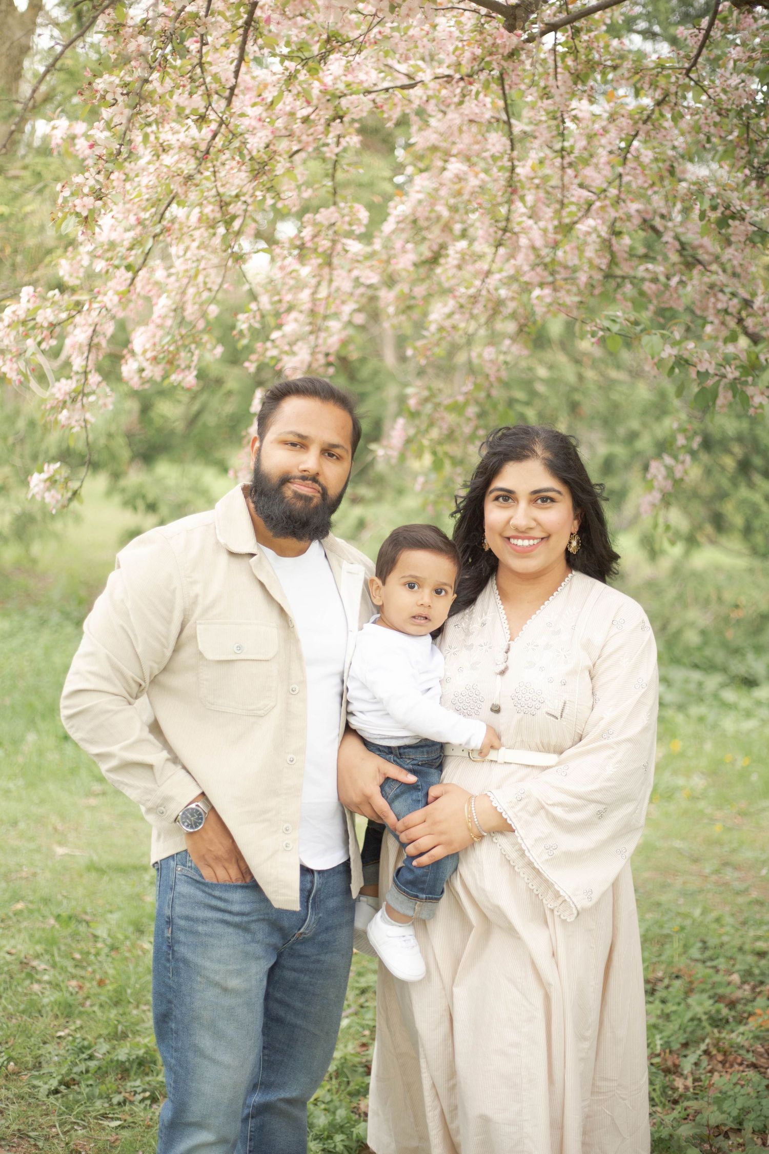 A family shares tender moments together under blooming cherry blossom trees in a spring garden setting.