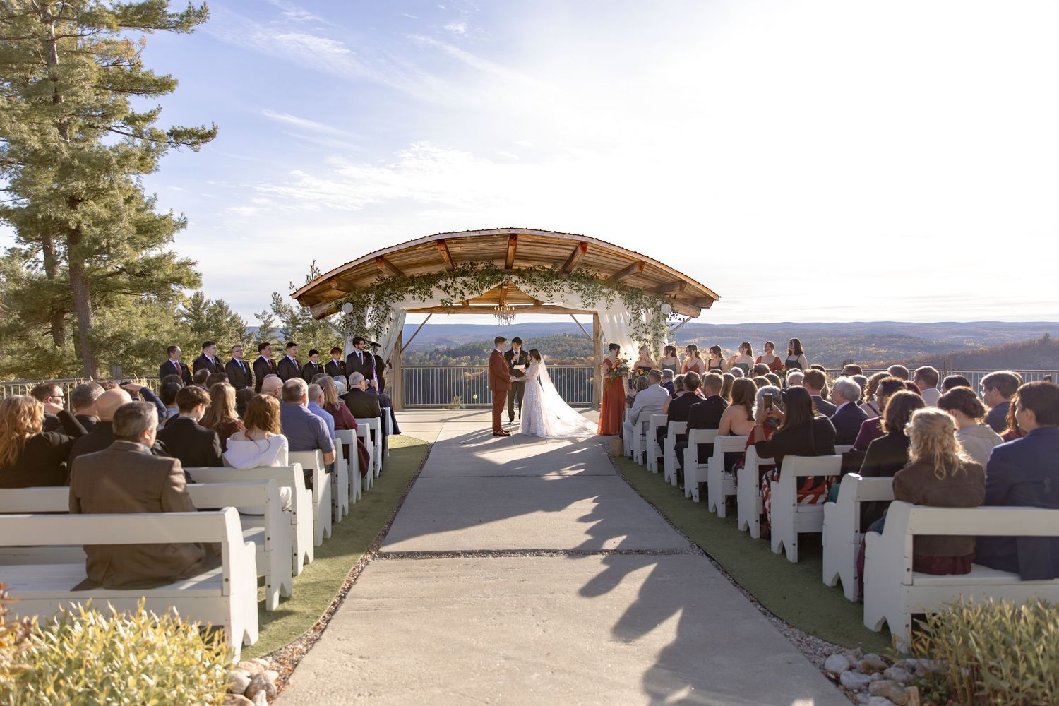 Panoramic view of an outdoor wedding ceremony setup with white chairs and mountain vista backdrop.