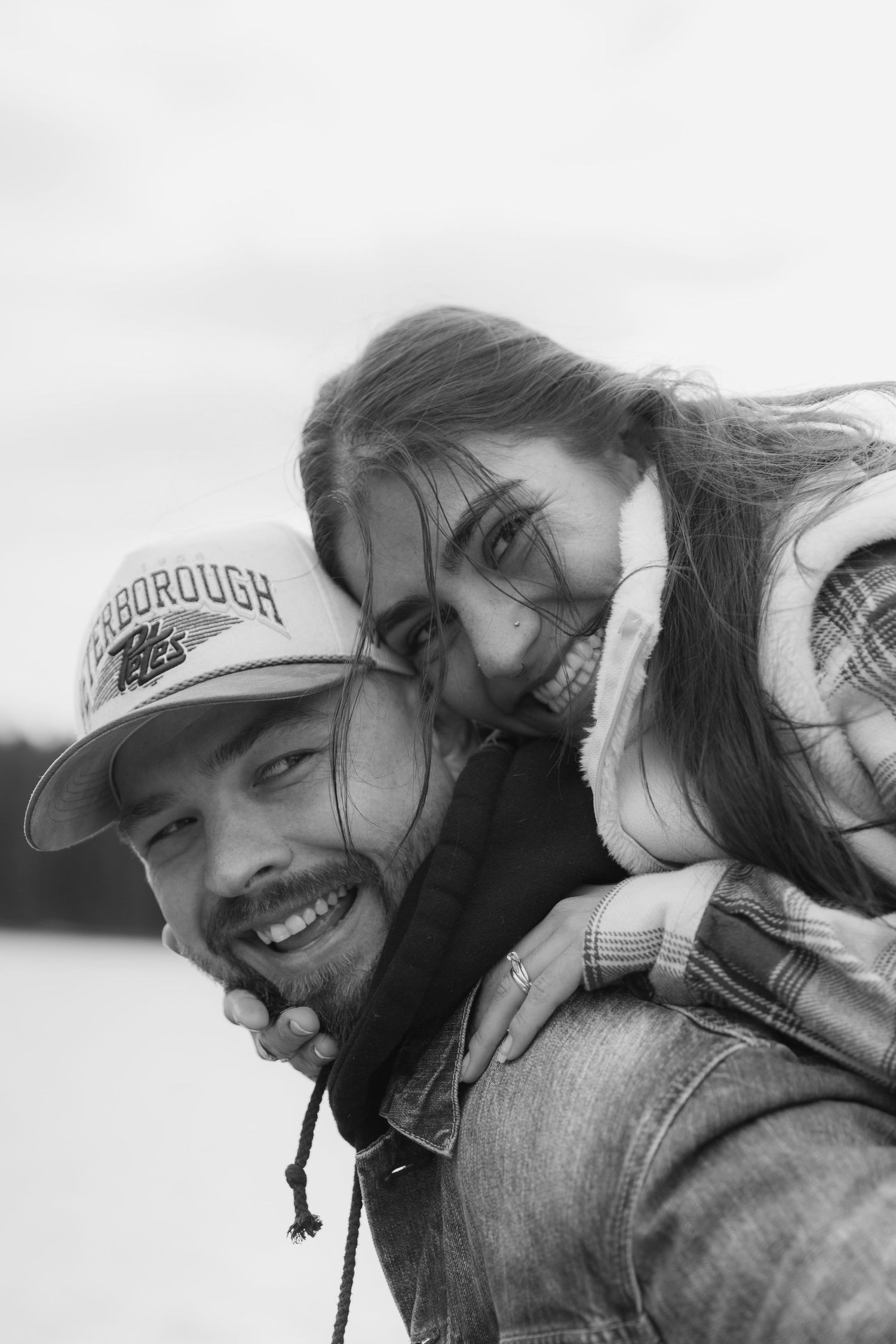 A black and white candid photo of three people smiling and embracing outdoors.
