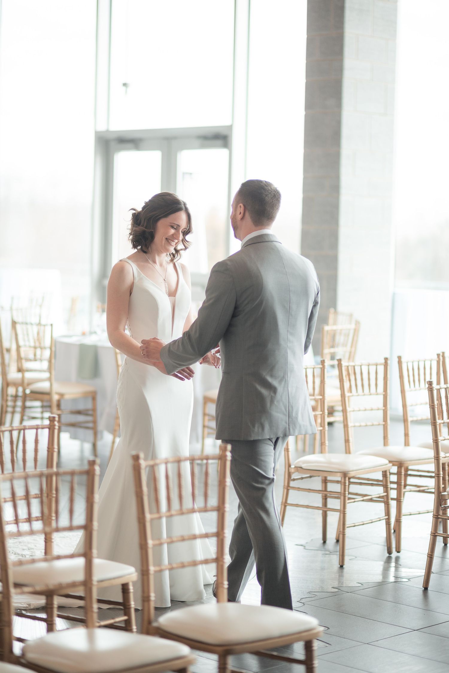 Bride and groom share a tender moment dancing in an elegant wedding reception venue with gold Chiavari chairs.