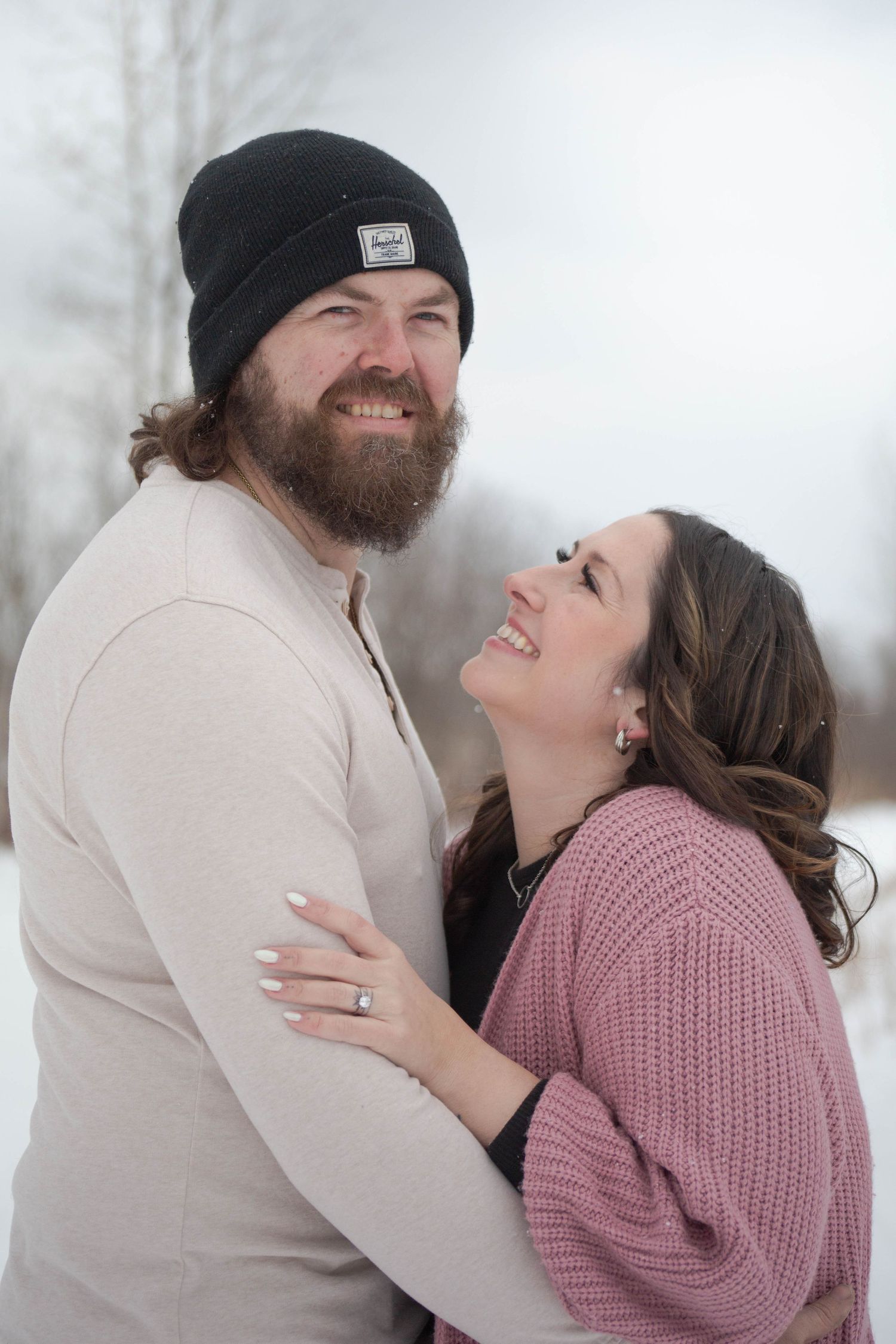 Happy couple sharing intimate moment while embracing outdoors in winter setting.
