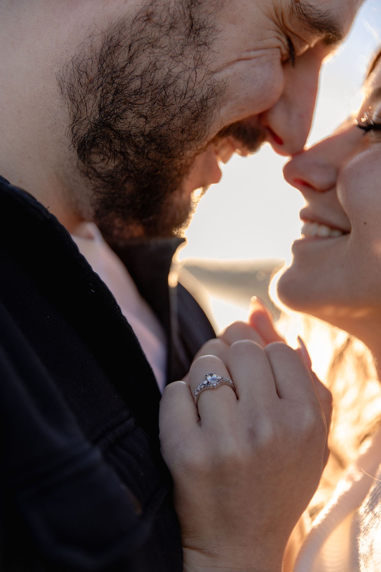 A romantic couple in silhouette sharing an intimate moment at sunset with warm golden light illuminating their faces.