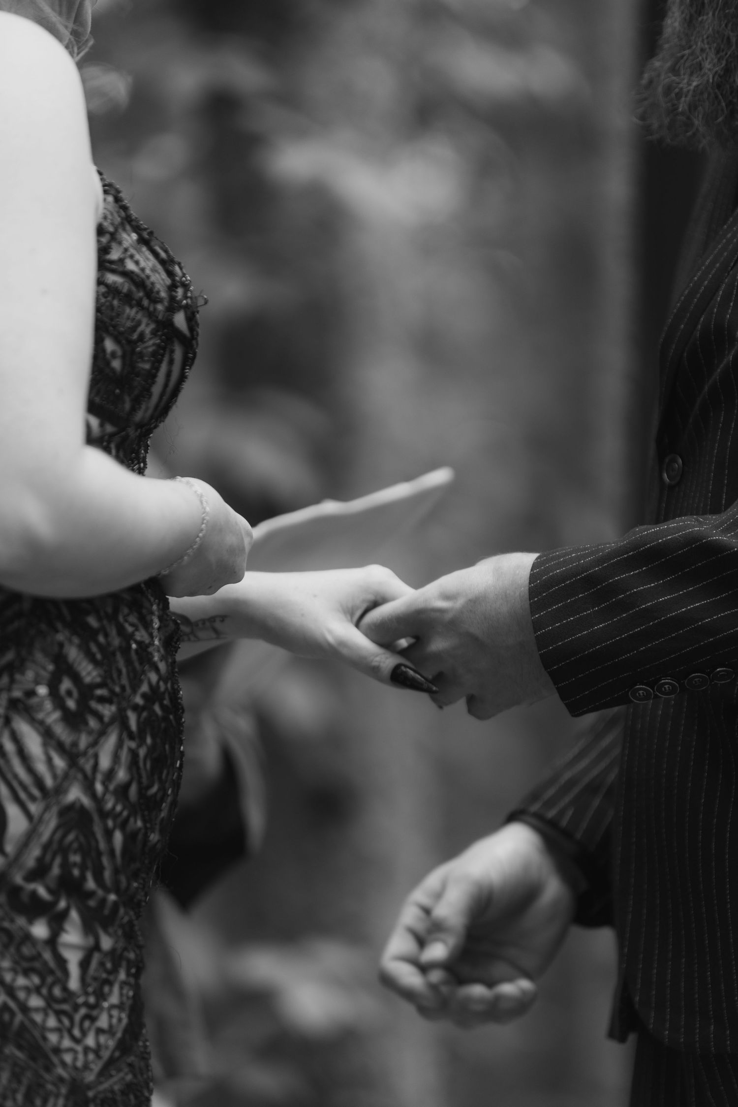 Two hands exchanging rings during an intimate black and white wedding ceremony moment.