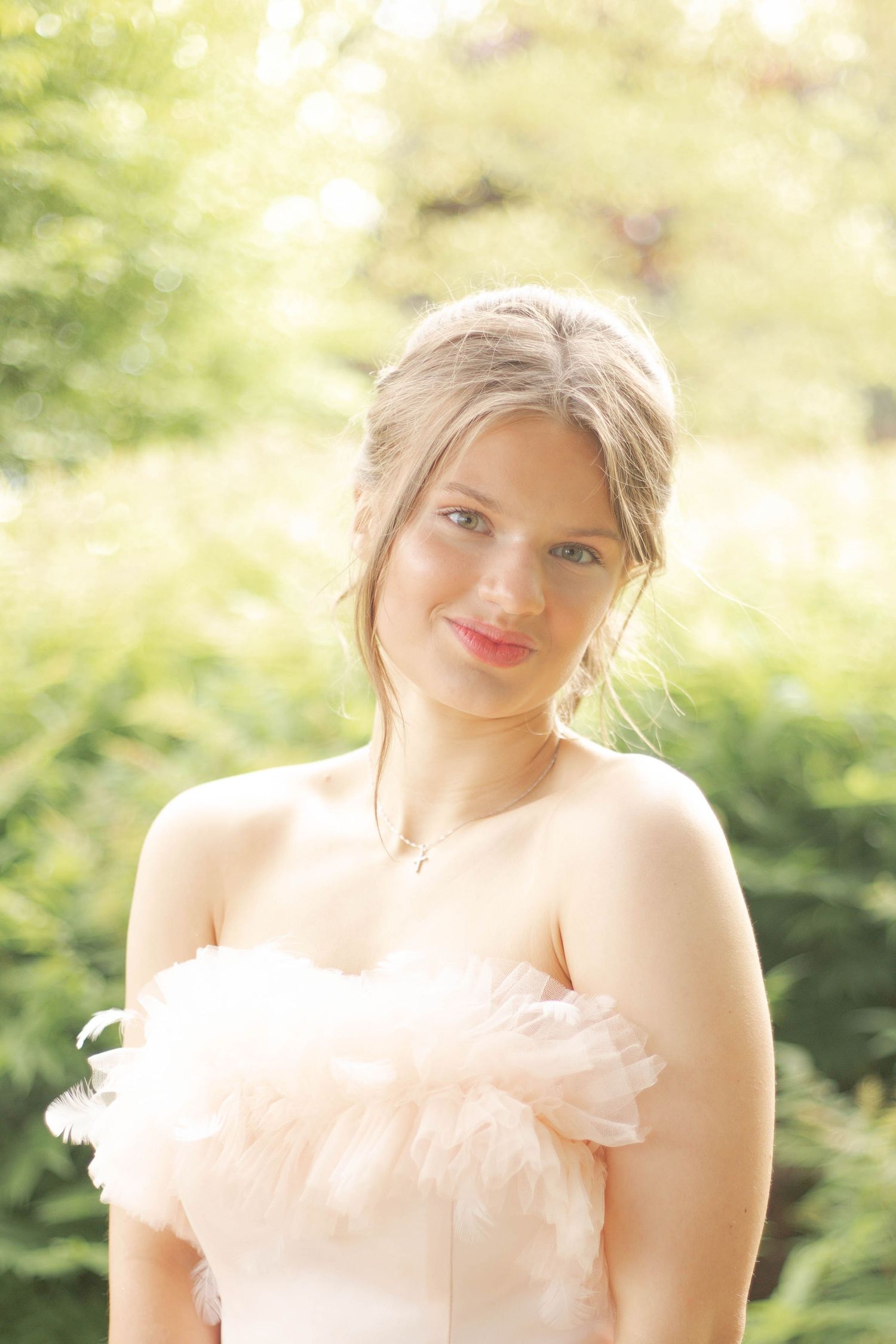 A soft portrait of a woman in a blush strapless gown with delicate tulle details.