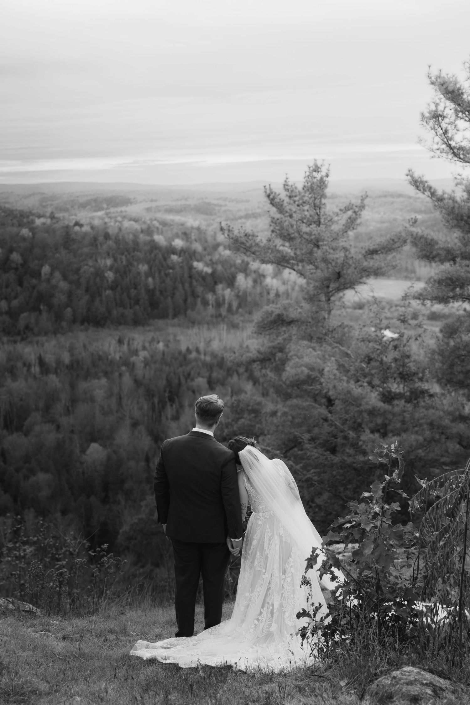 Black and white panoramic sequence showing a couple enjoying a scenic mountain overlook on their wedding day.