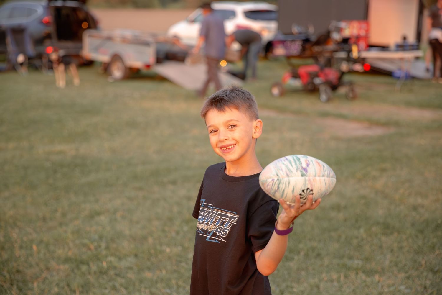 Young athlete throwing a volleyball on a grassy field during an outdoor summer activity session.