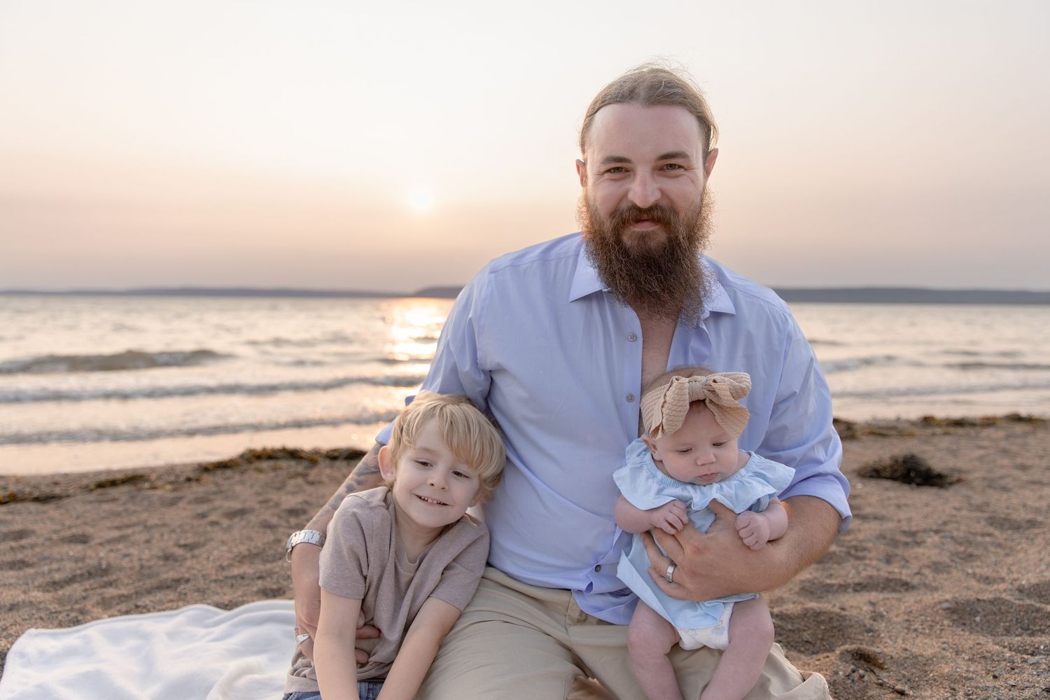 Family enjoys sunset moment together on sandy beach during golden hour photography session.