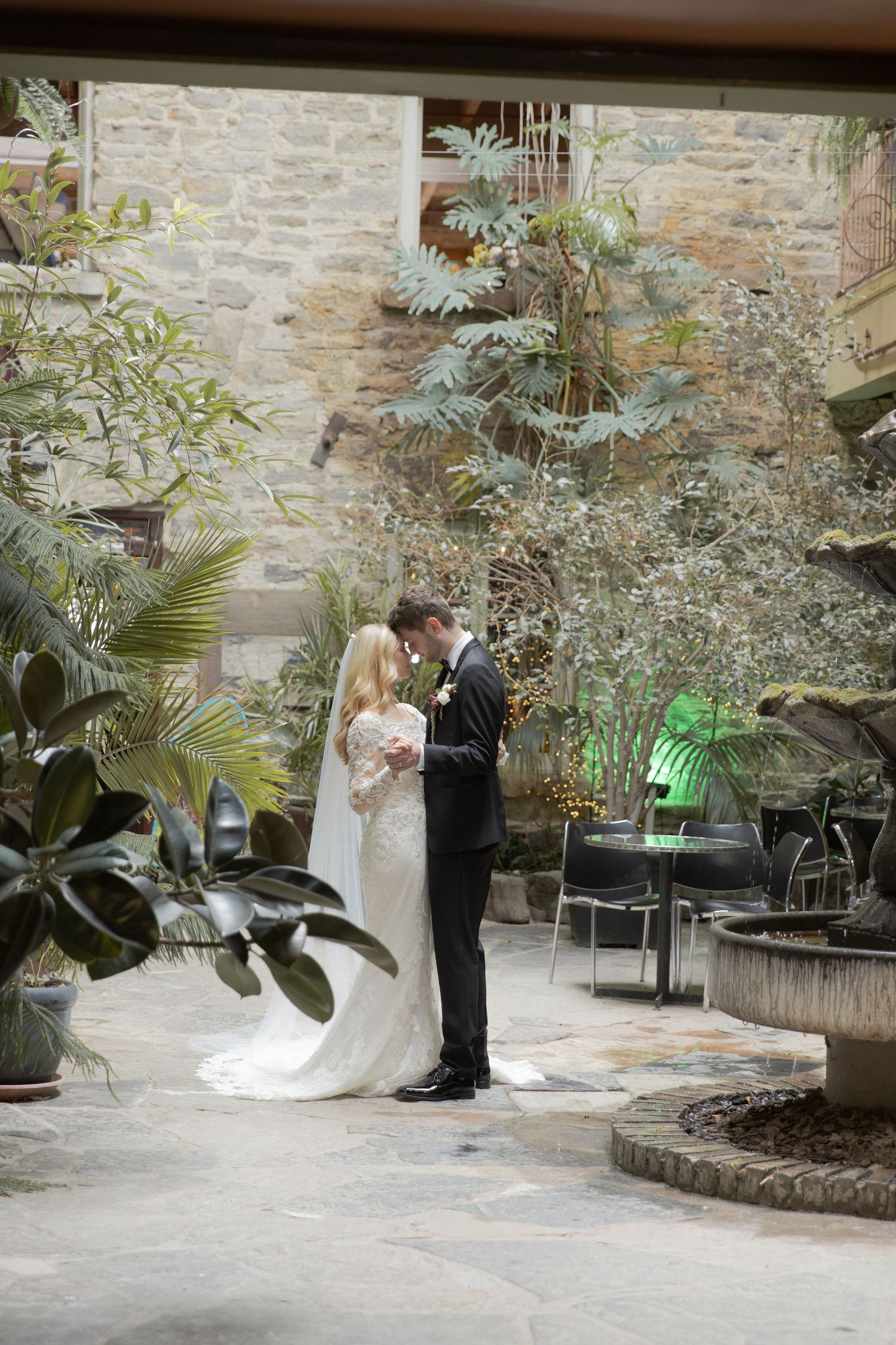 A romantic wedding sequence showing a couple dancing together in a stone-walled courtyard with lush tropical plants.