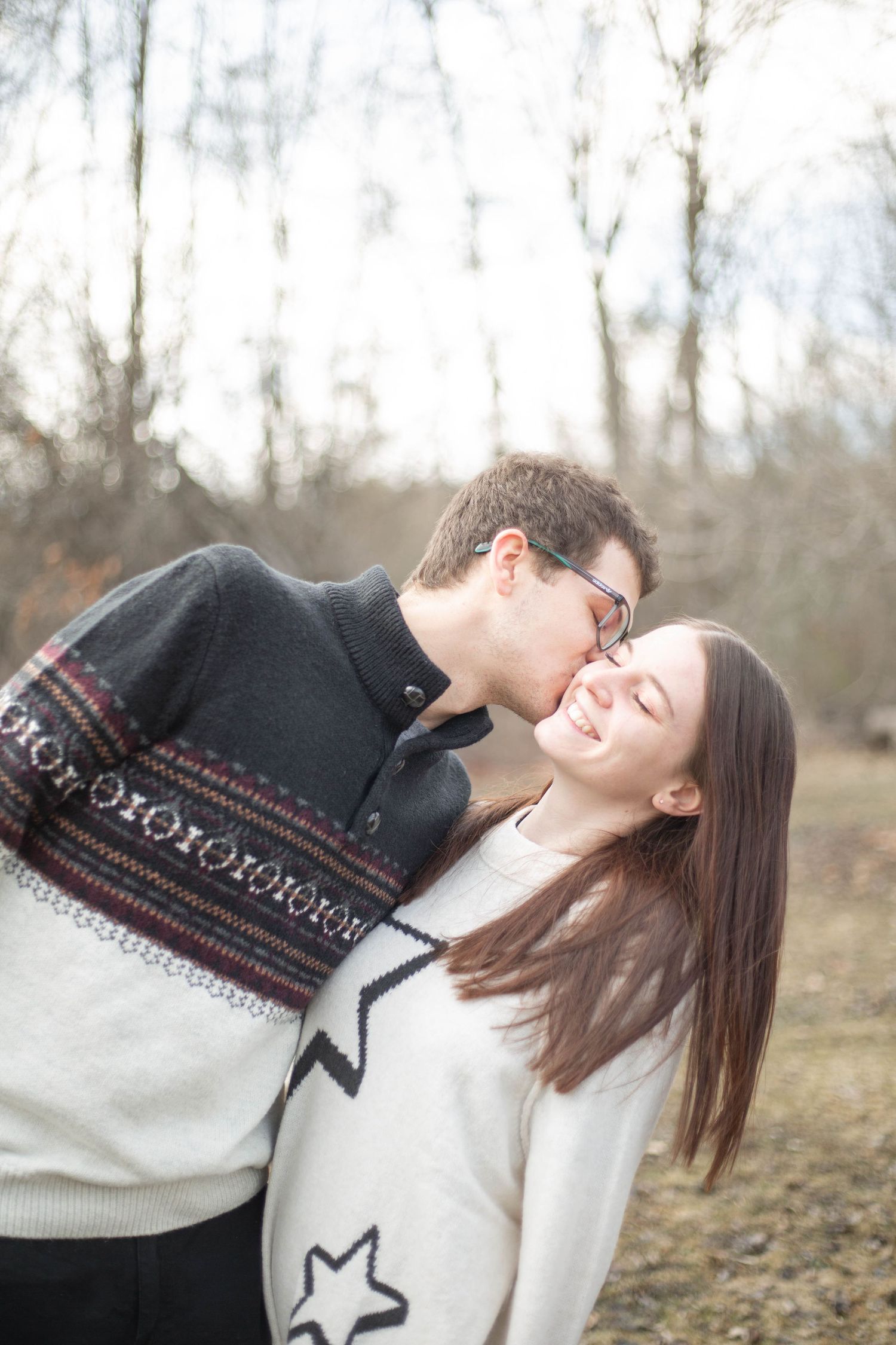 A romantic couple wearing cozy sweaters share an intimate moment outdoors in spring