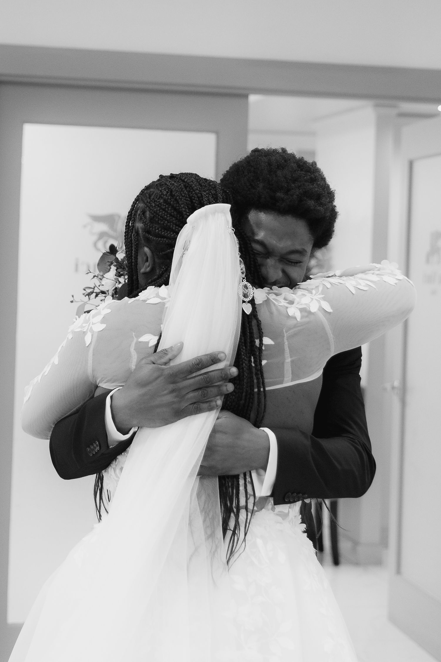 Black and white photo of a bride and groom sharing an emotional embrace on their wedding day.