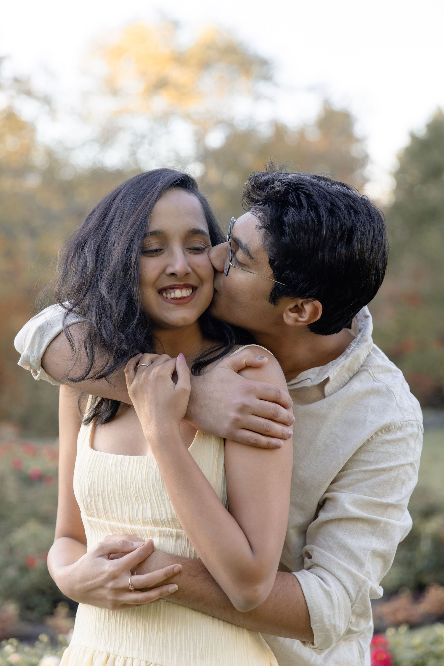 A romantic couple shares tender moments in a garden setting during golden hour.