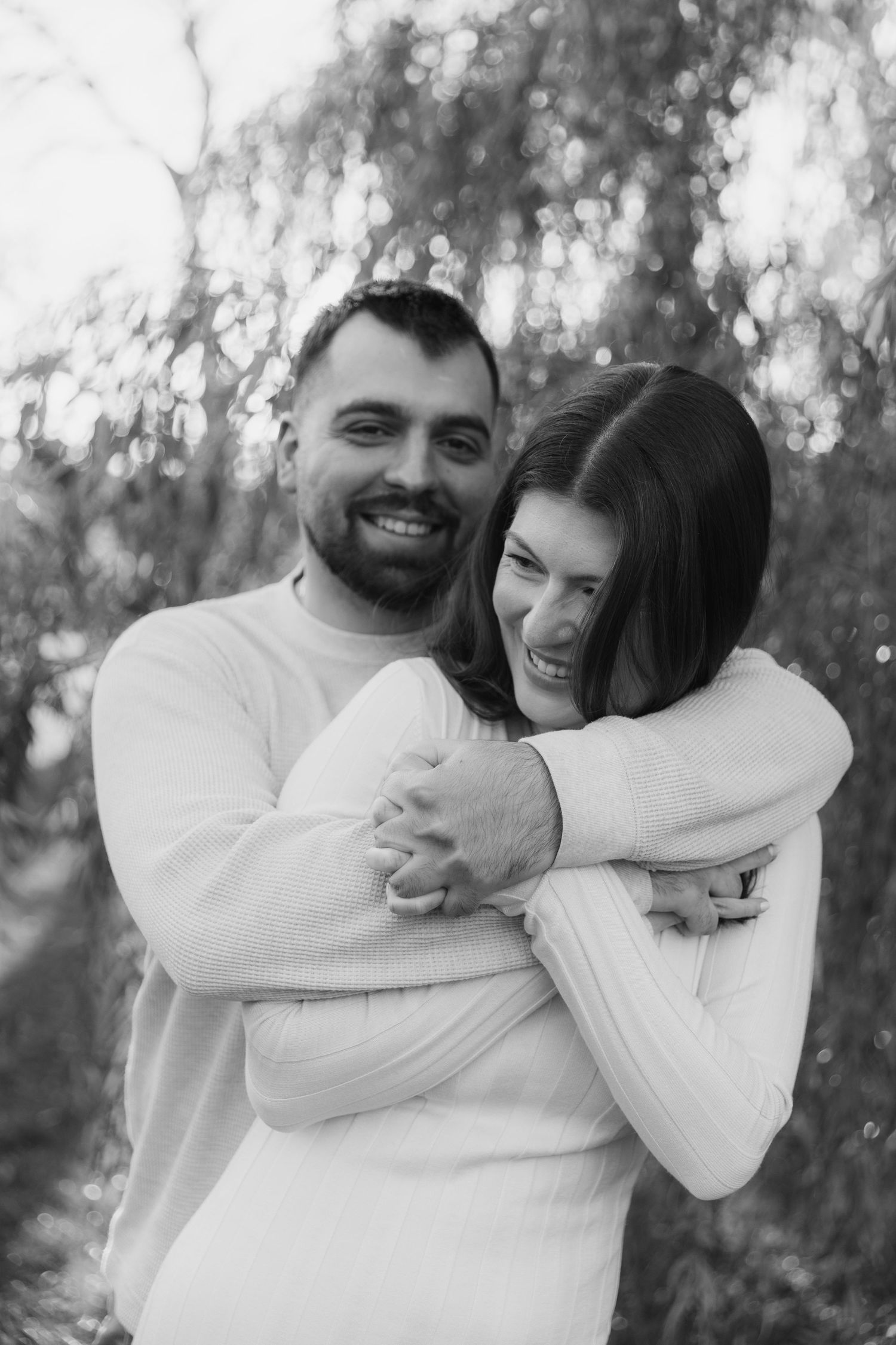 A series of black and white photos showing a couple embracing and laughing together in a natural outdoor setting.