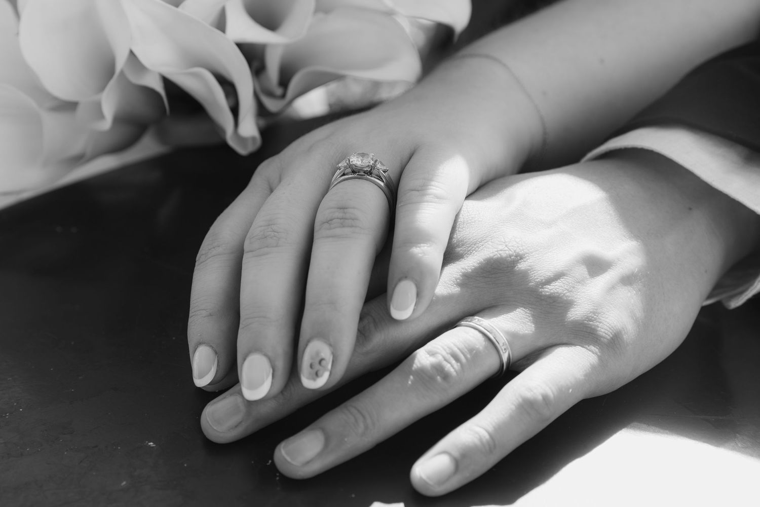 Close-up black and white sequence of hands placing rings on fingers during a wedding ceremony.
