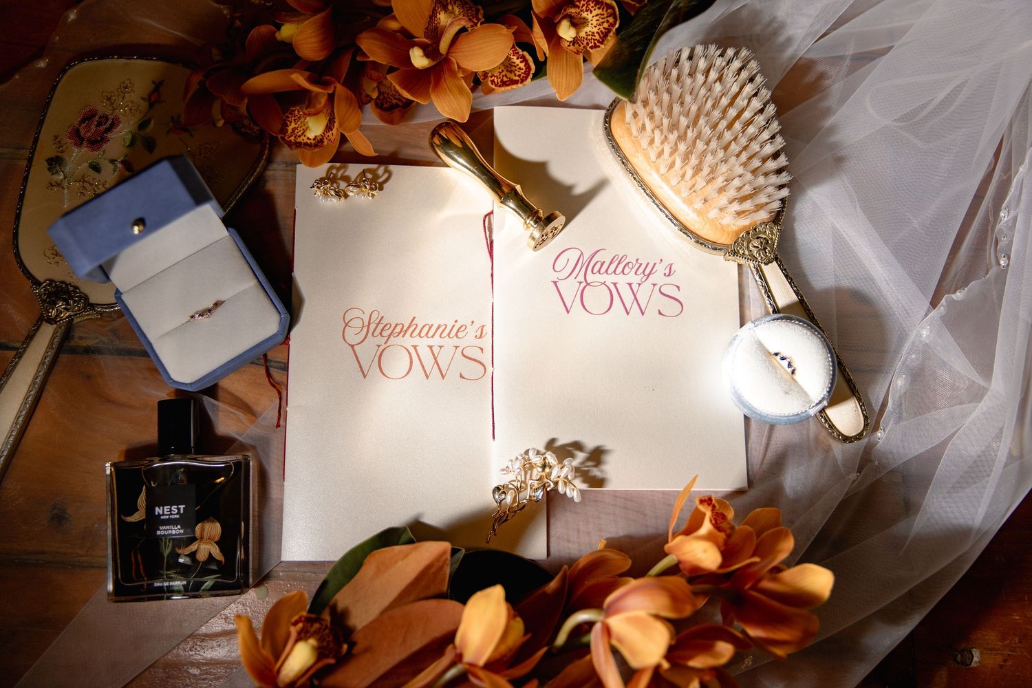 Wedding vows book surrounded by autumn leaves, perfume bottle, hairbrush and white tulle on a light surface.