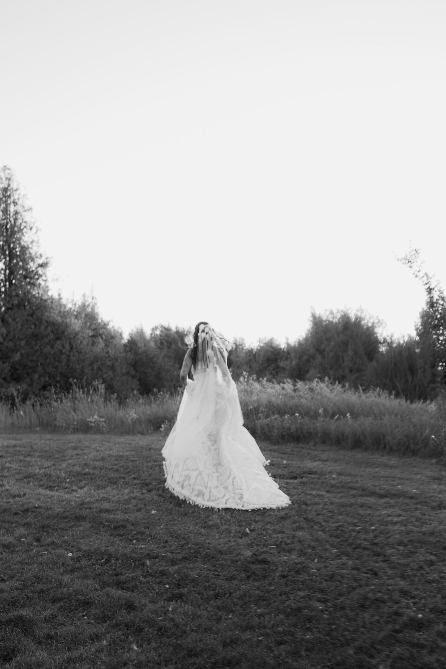 A sequence of black and white photos showing a white wedding dress in a grassy field at dusk.