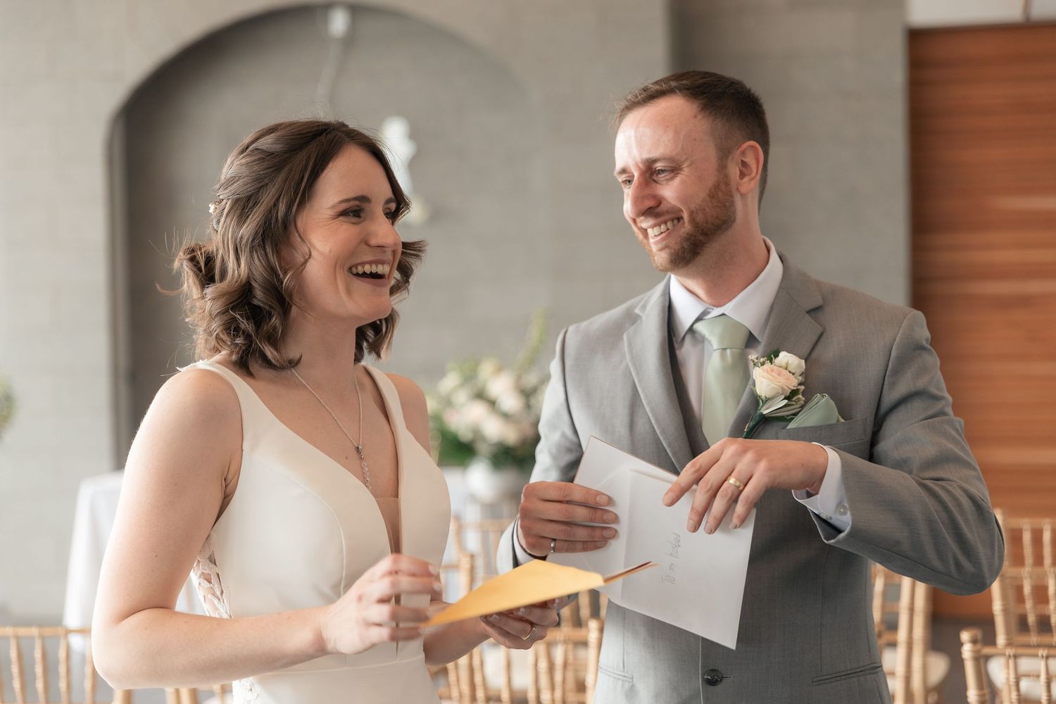 Bride and groom laughing together during wedding ceremony, exchanging vows in elegant venue.