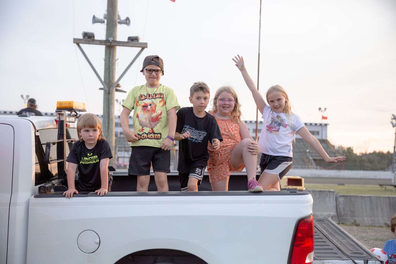 Group of people pose cheerfully outdoors next to solar panels on a bright sunny day.
