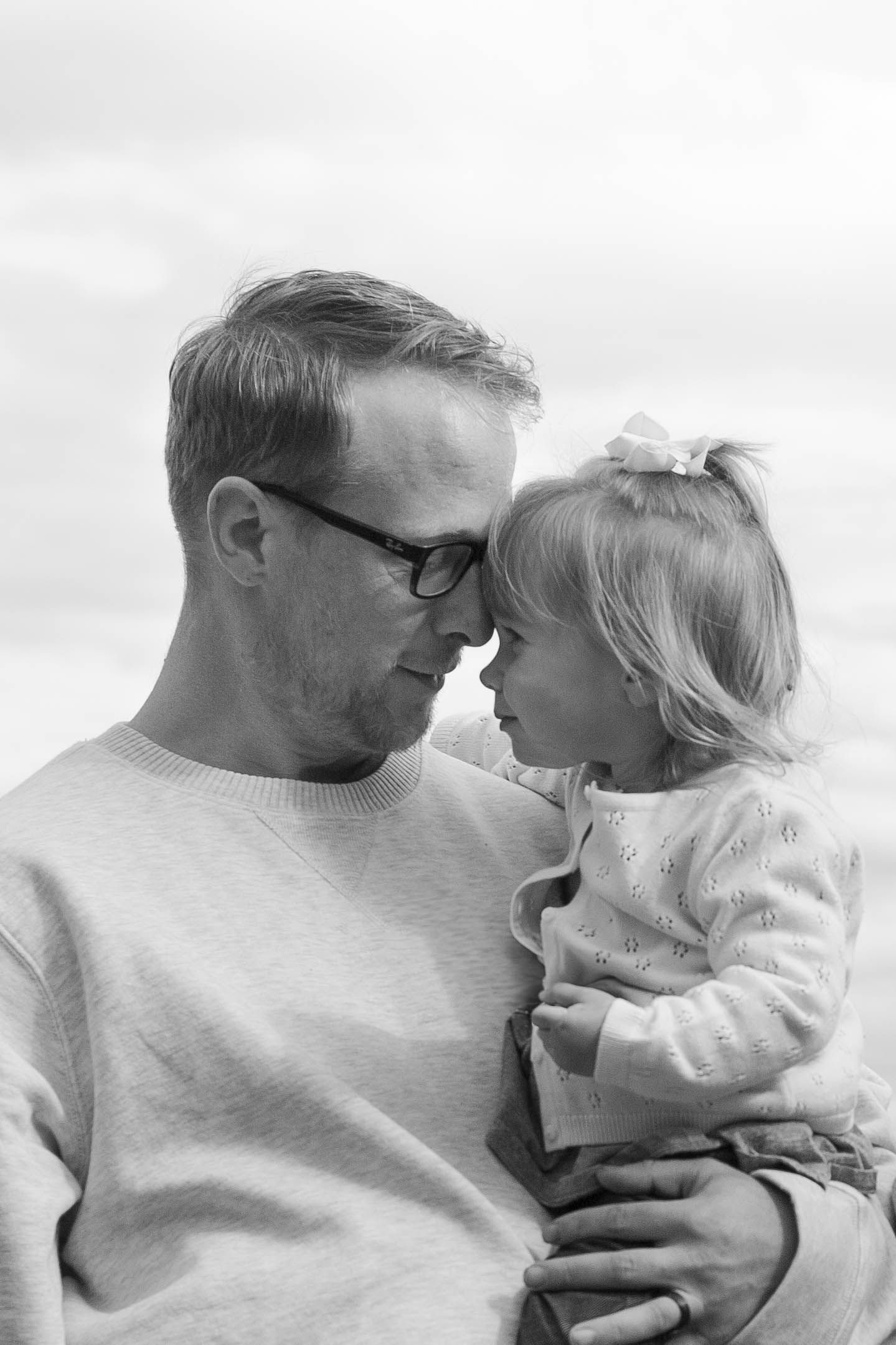 A tender black and white portrait of a dad and young child sharing an intimate moment together.