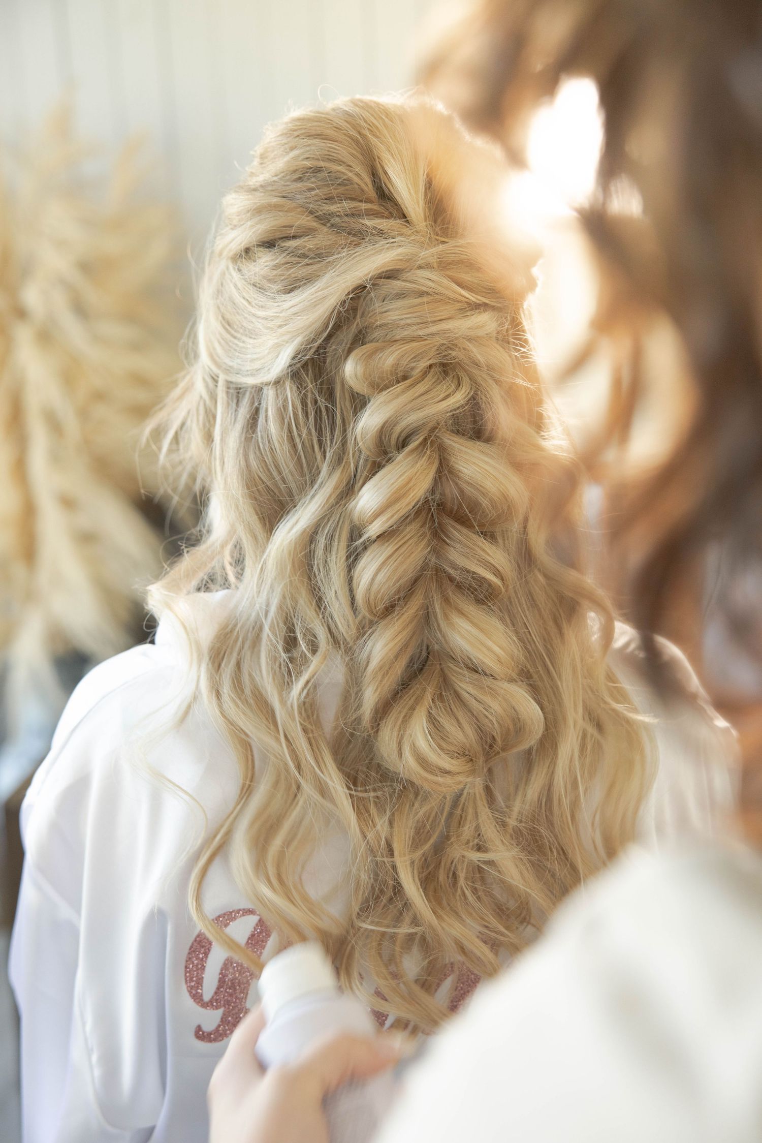 Beautiful loose braided hairstyle with soft blonde waves cascading down the back.