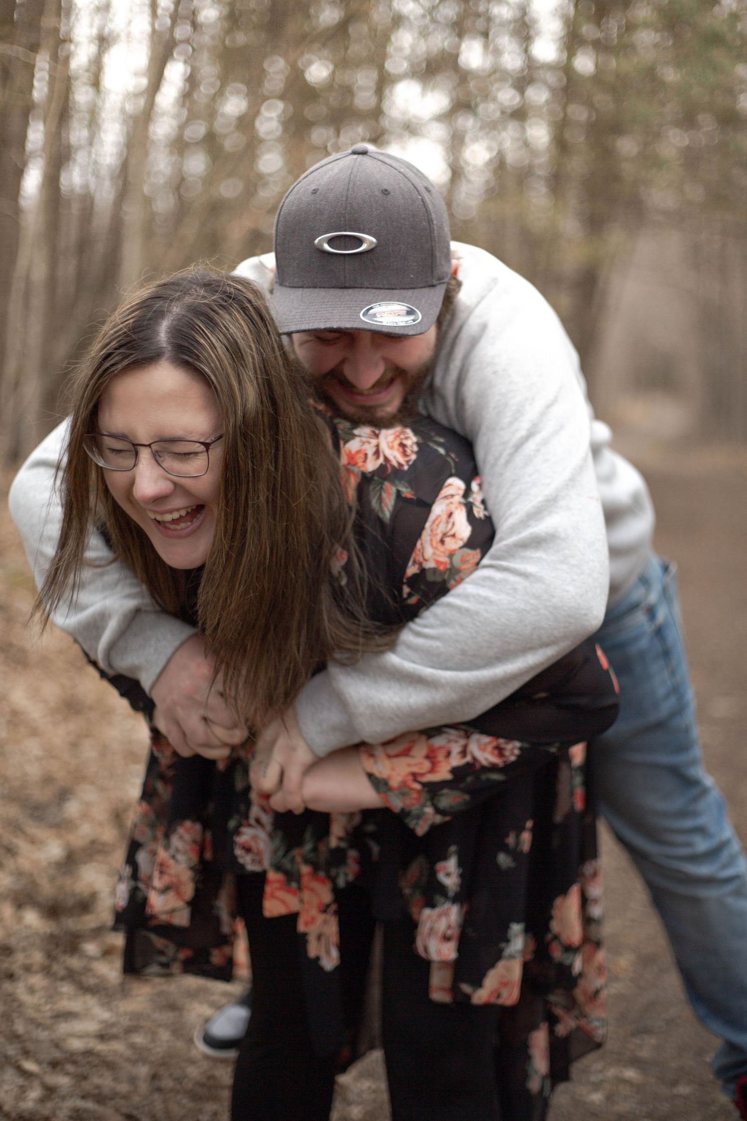 A couple shares a playful and intimate moment together on a forest trail during autumn.