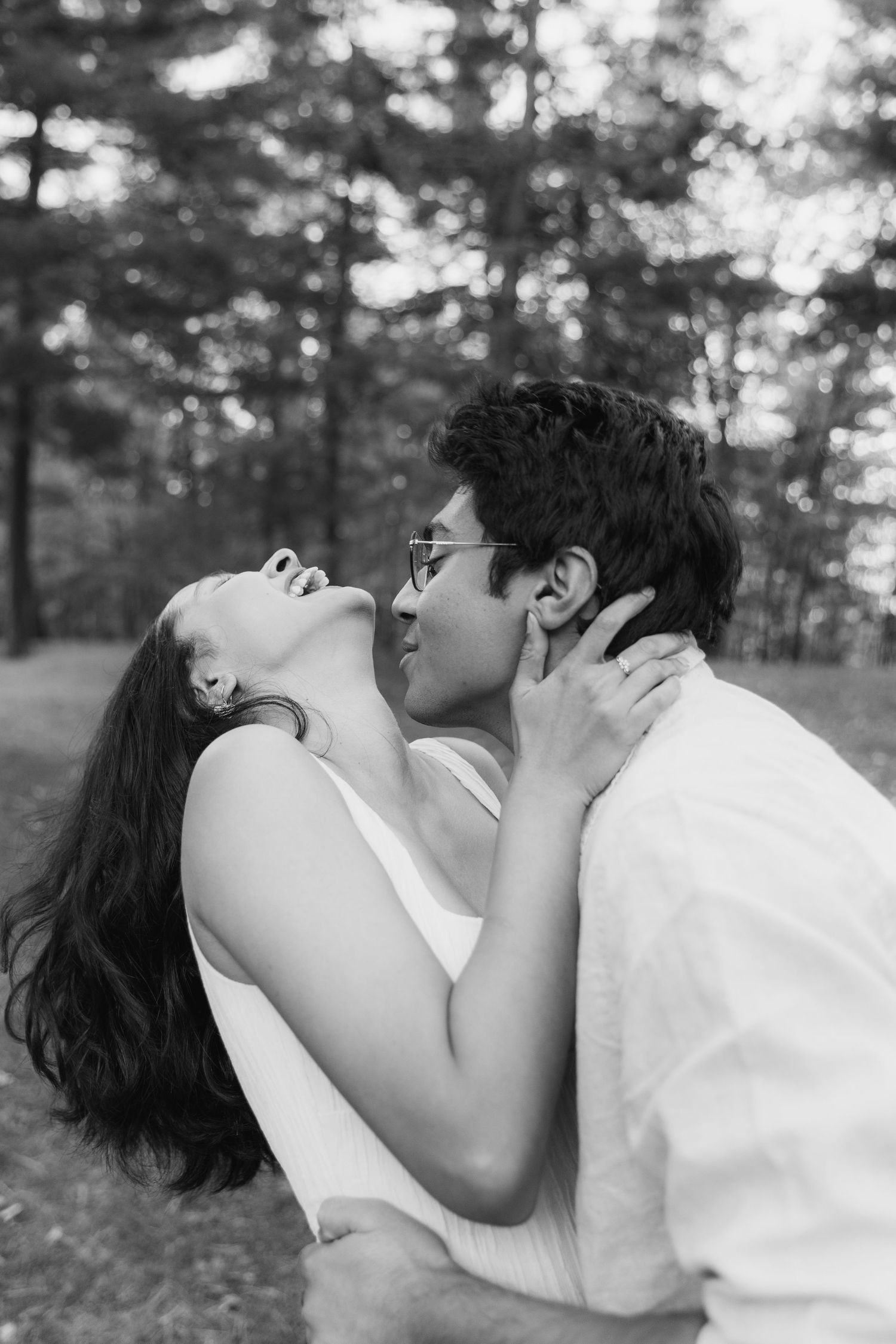 A romantic black and white photo series shows a couple in white clothing sharing an intimate kiss outdoors.