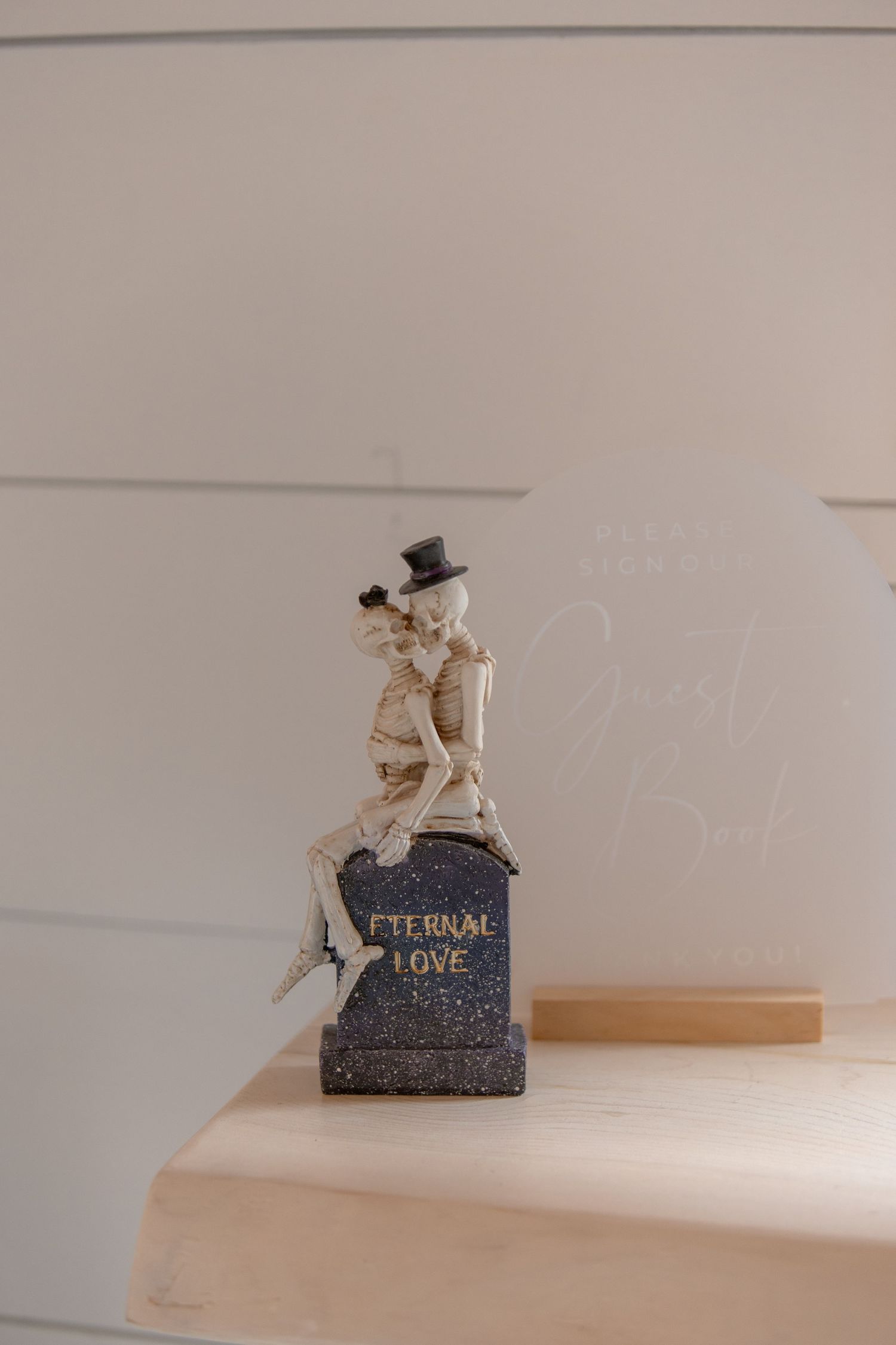 A series of photos showing a small decorative skeleton figure sitting on a dark pedestal against a white wall.